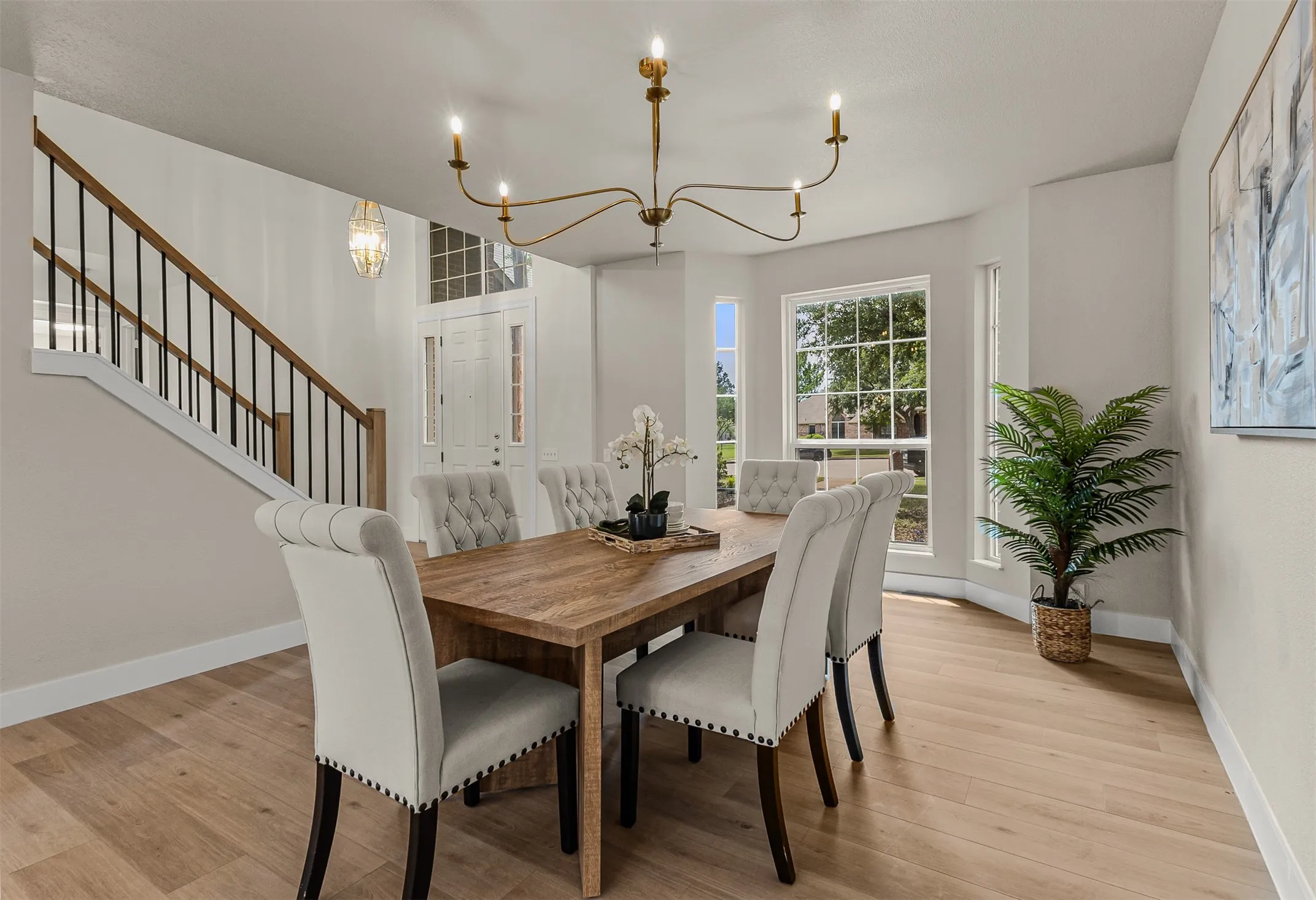 Spacious dining area featuring wood-finish flooring, a contemporary chandelier, and a bay window with multiple panes