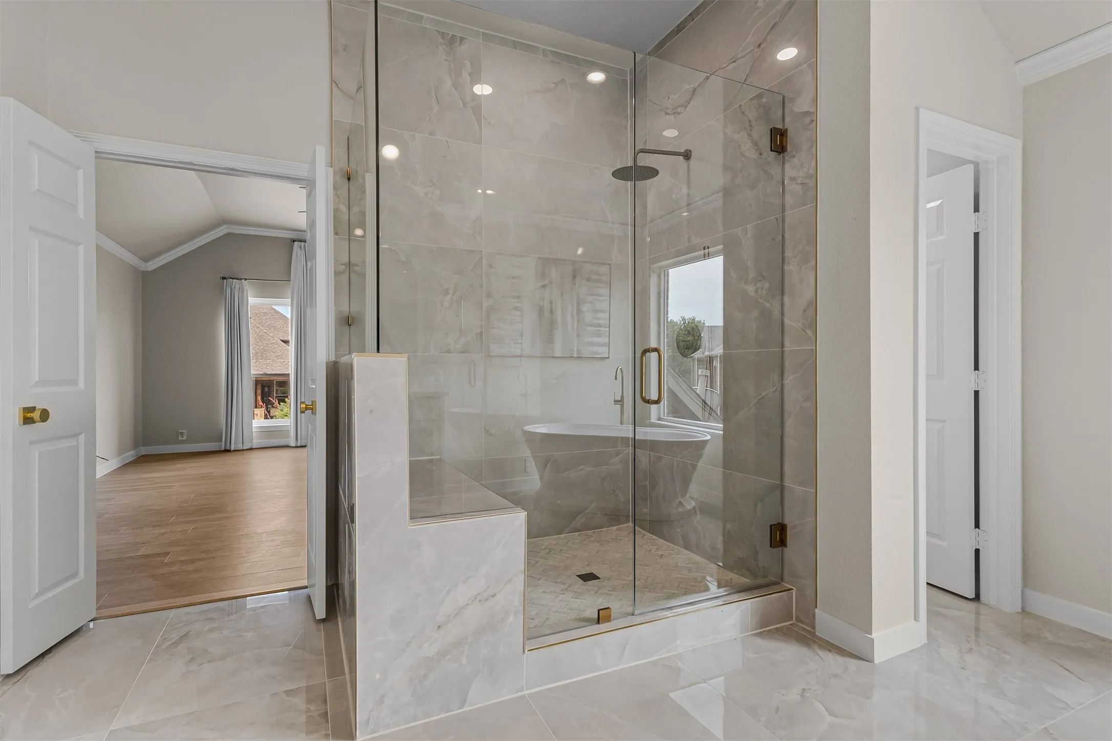 Glass-enclosed walk-in shower featuring a built-in bench, large format tile, a rain showerhead, and a fixed window