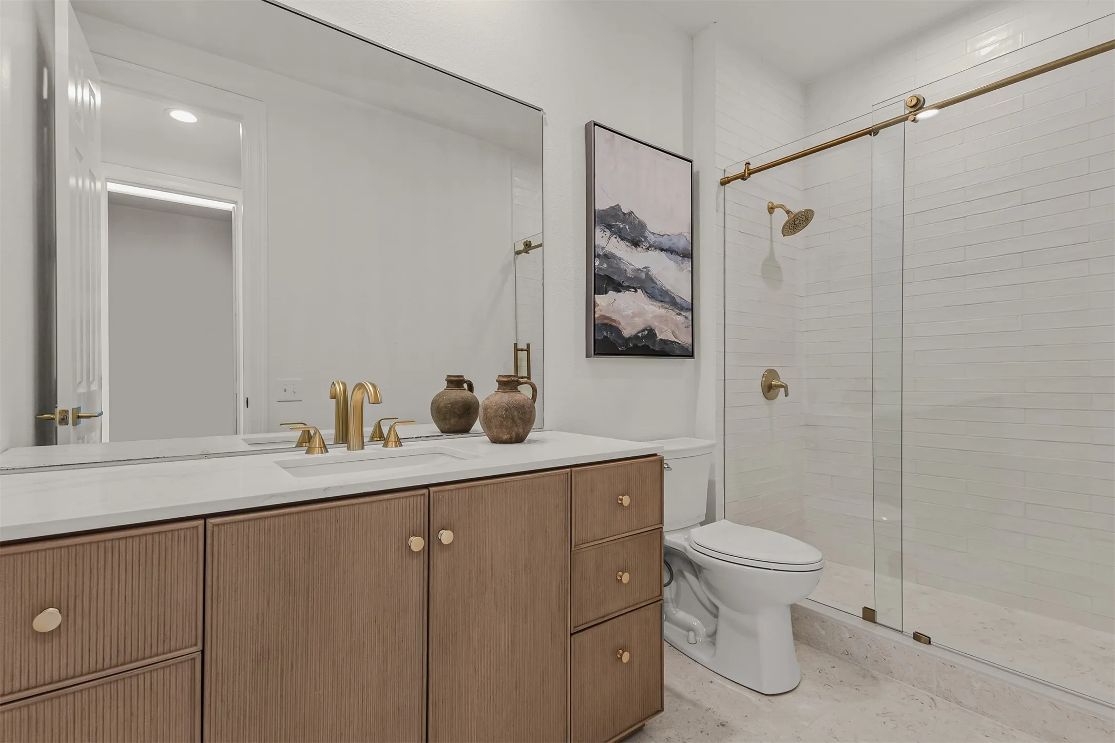 Bathroom featuring a double vanity with stone countertop, integrated sink, and brass-finish fixtures
