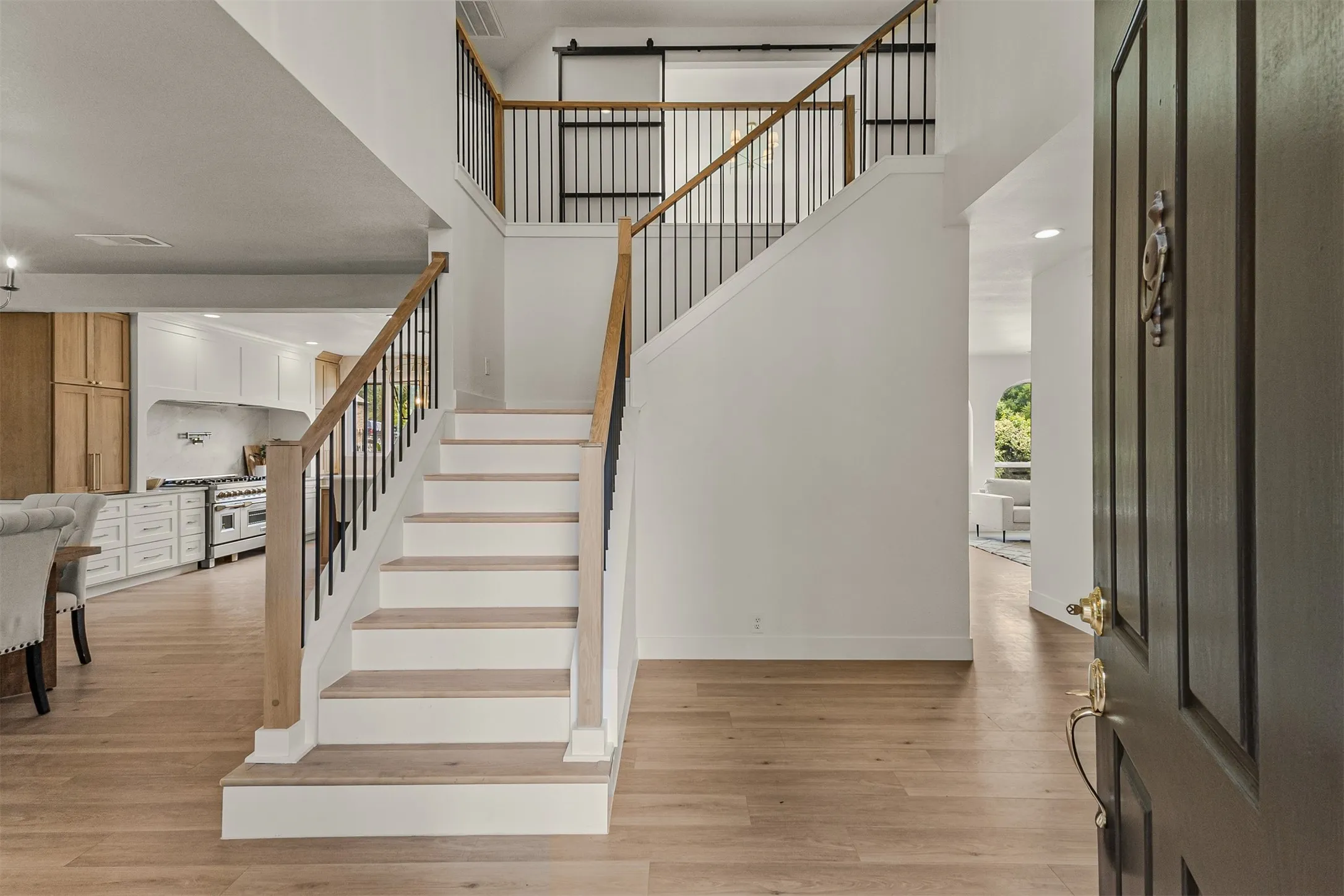 Grand entryway featuring a staircase with wood-finish handrails and black metal balusters