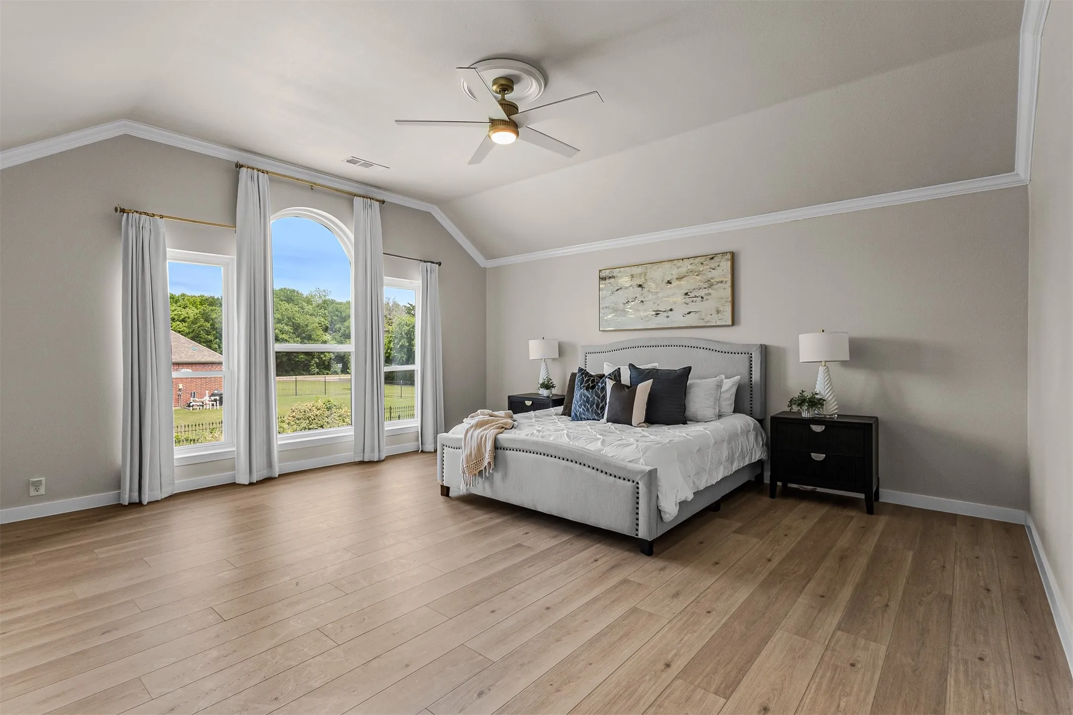 Vaulted ceiling featuring a ceiling fan, crown molding, and light wood-finish flooring