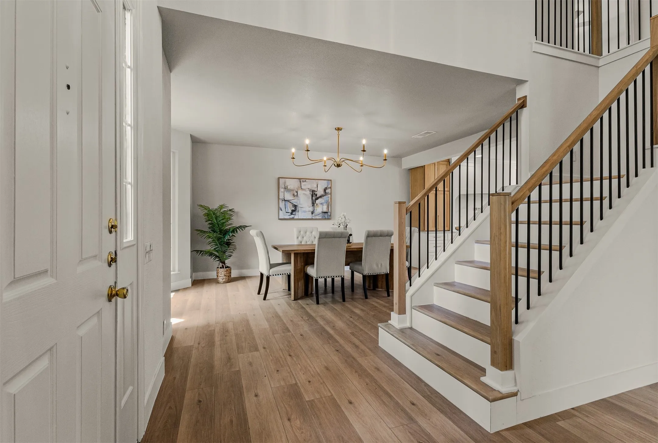 Entryway featuring wood-finish flooring, a white paneled front door with a vertical window pane, and a modern staircase with wood handrails and black metal balusters