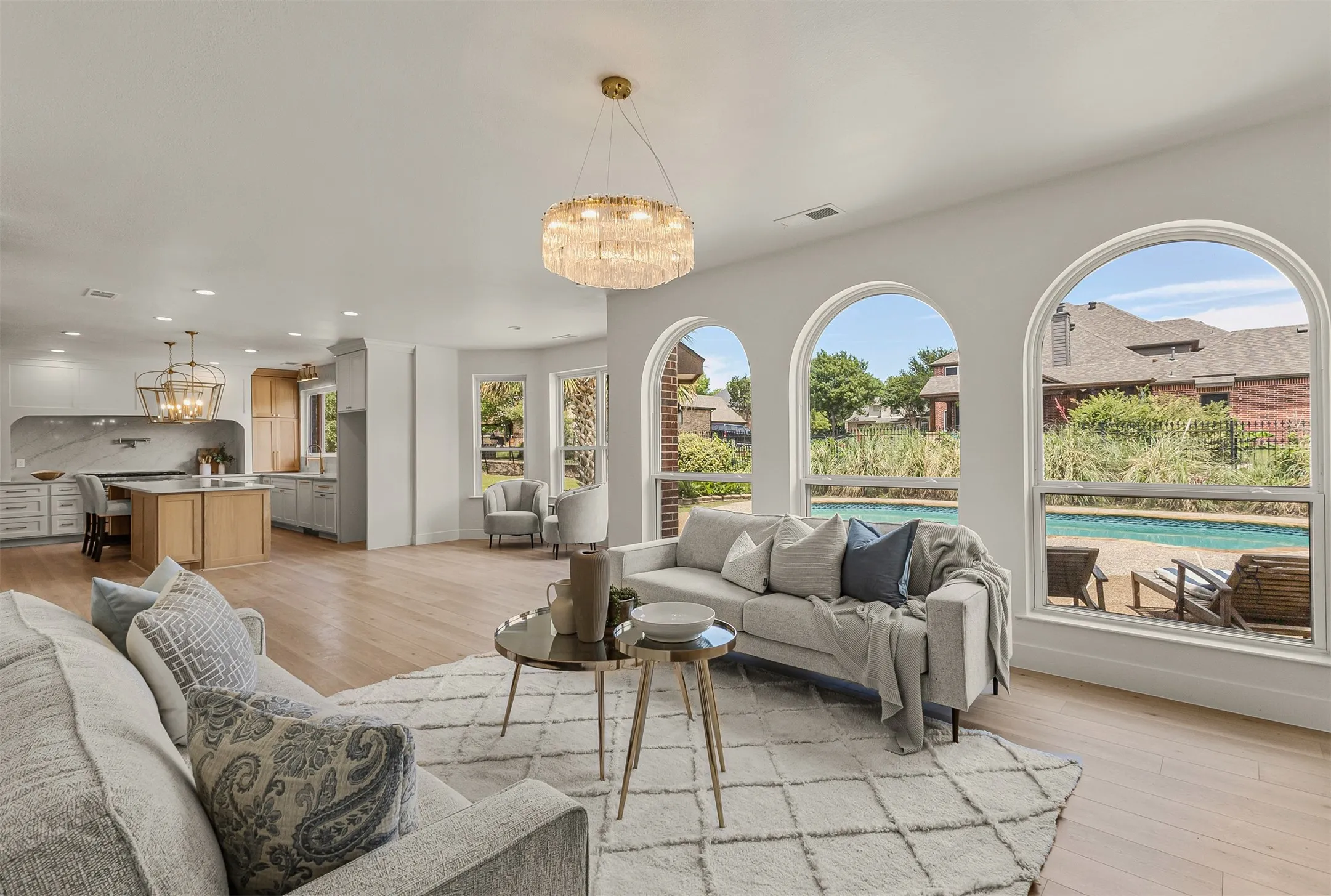 Spacious living area featuring light wood-finish flooring and a contemporary chandelier