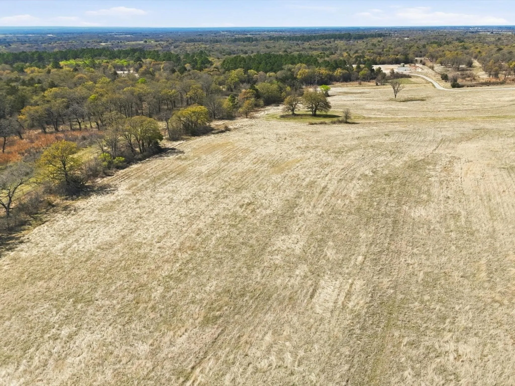 Pasture with 1 of 2 stock tanks on property, fencing, and LBJ National Grasslands beyond