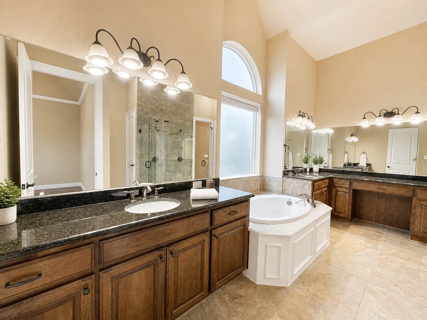 Spacious bathroom featuring dual vanities with dark granite countertops and wood cabinetry