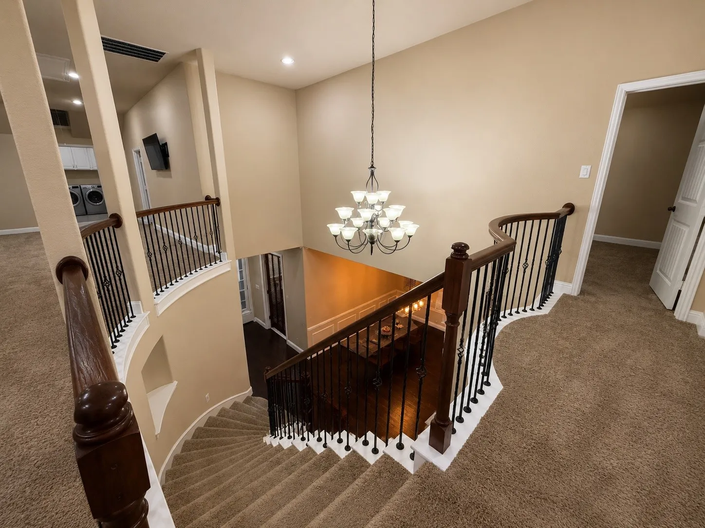 Carpeted staircase with dark wood handrails and wrought iron balusters