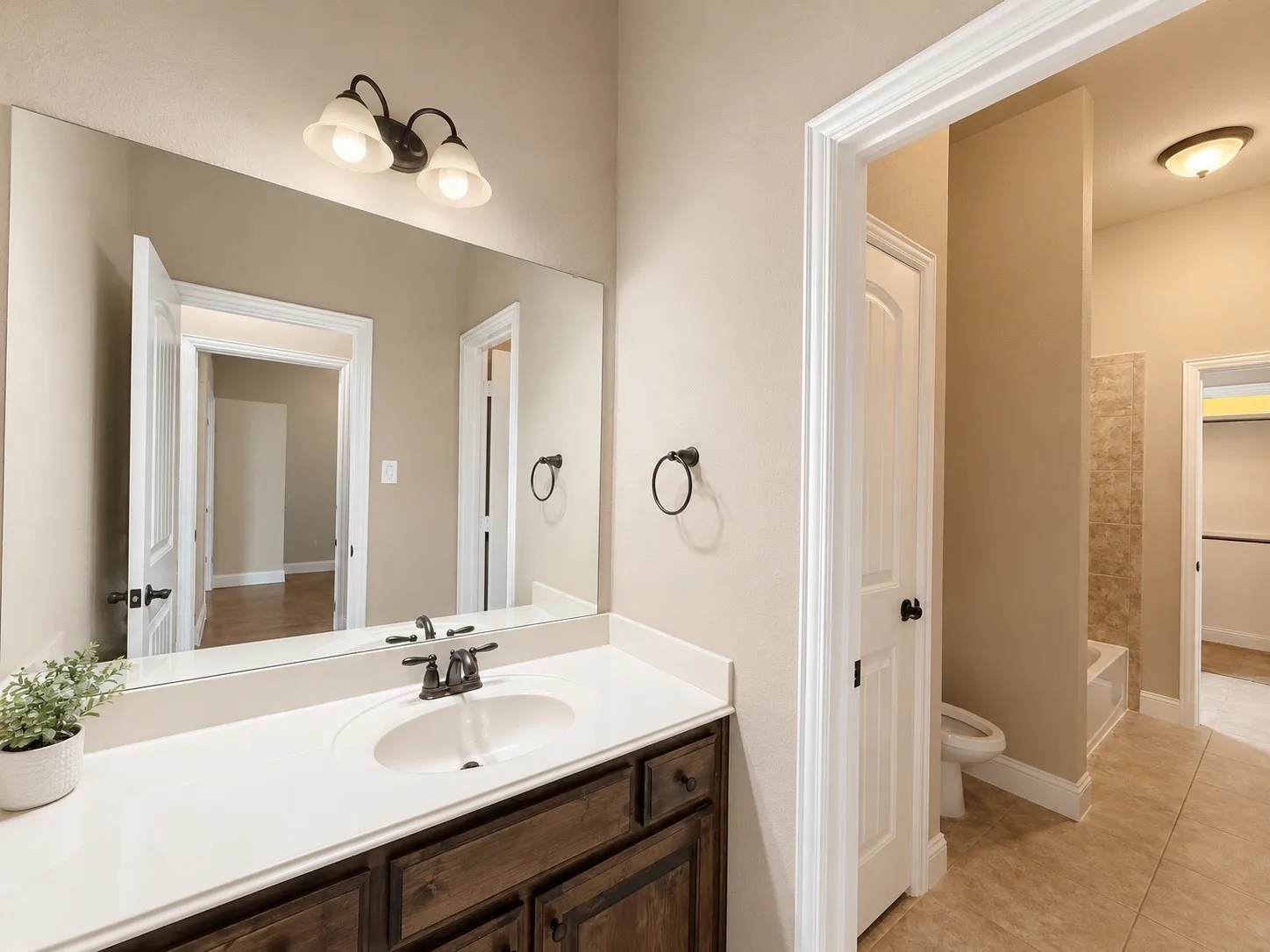Bathroom vanity featuring a single sink with a dark bronze faucet, a white countertop, and a dark wood cabinet