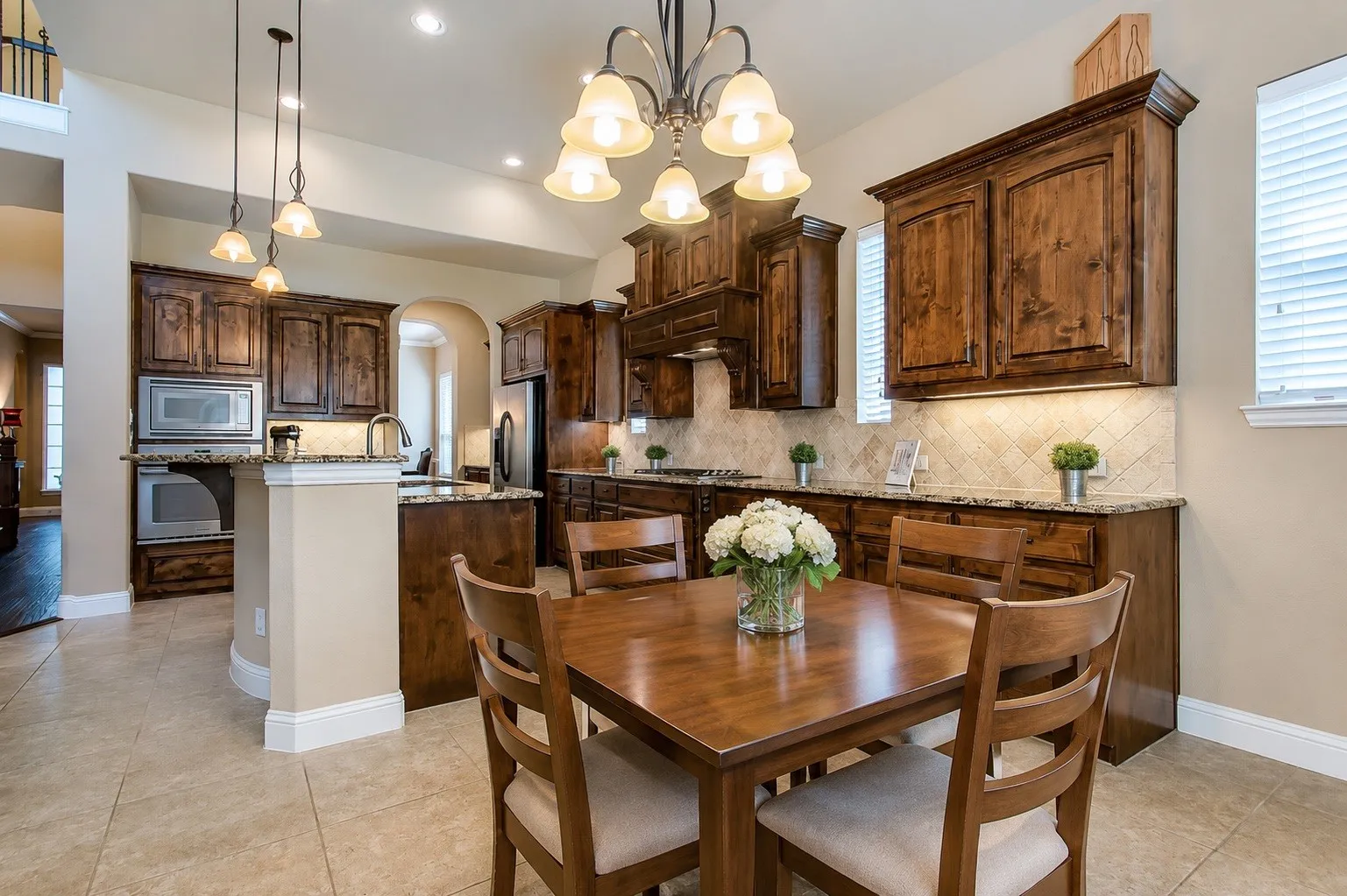 Kitchen dining area featuring a square wood table and chairs, recessed lighting, and a multi-light chandelier