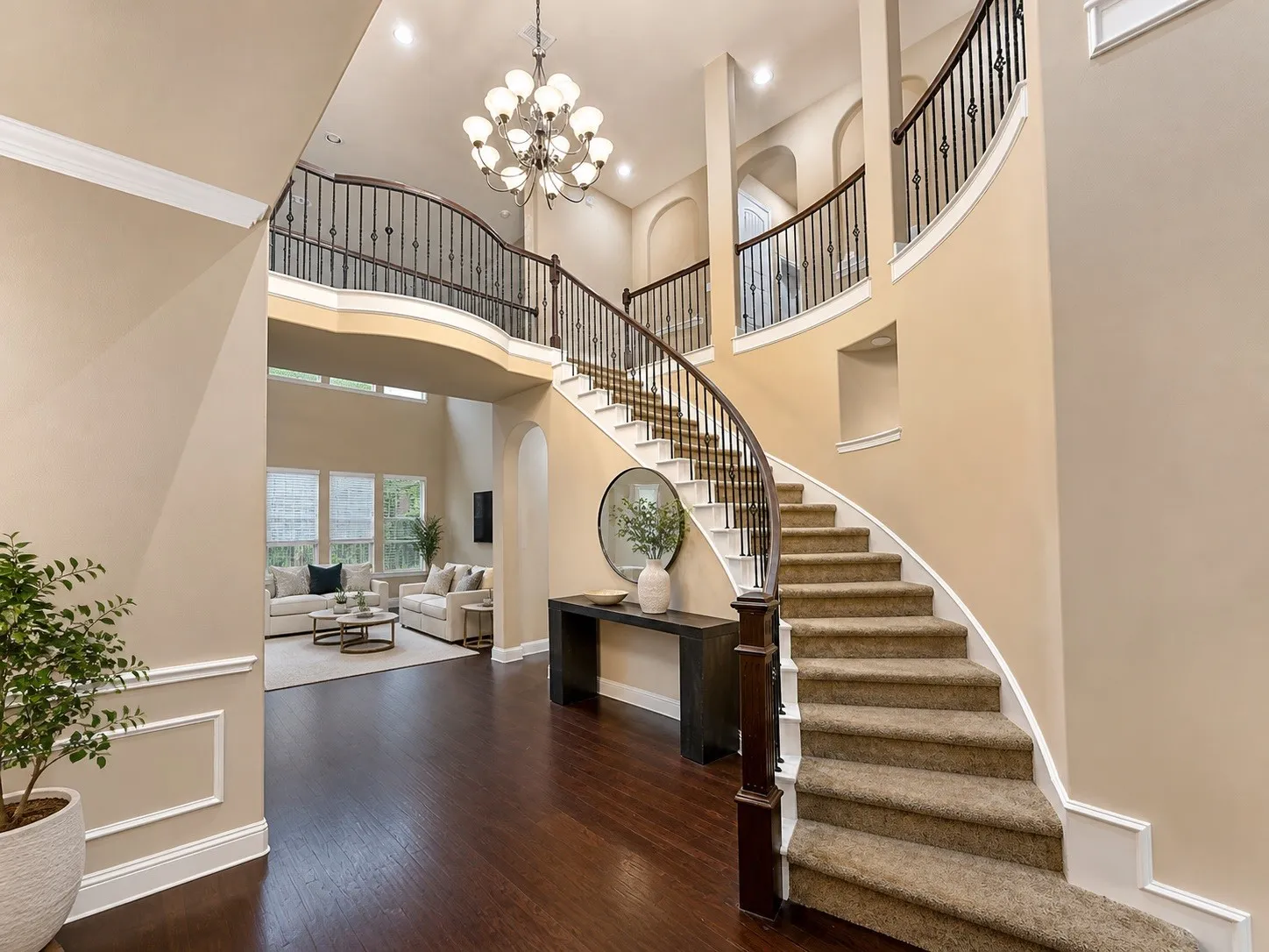 Grand entryway featuring a curved staircase with carpeted treads and wrought iron balusters