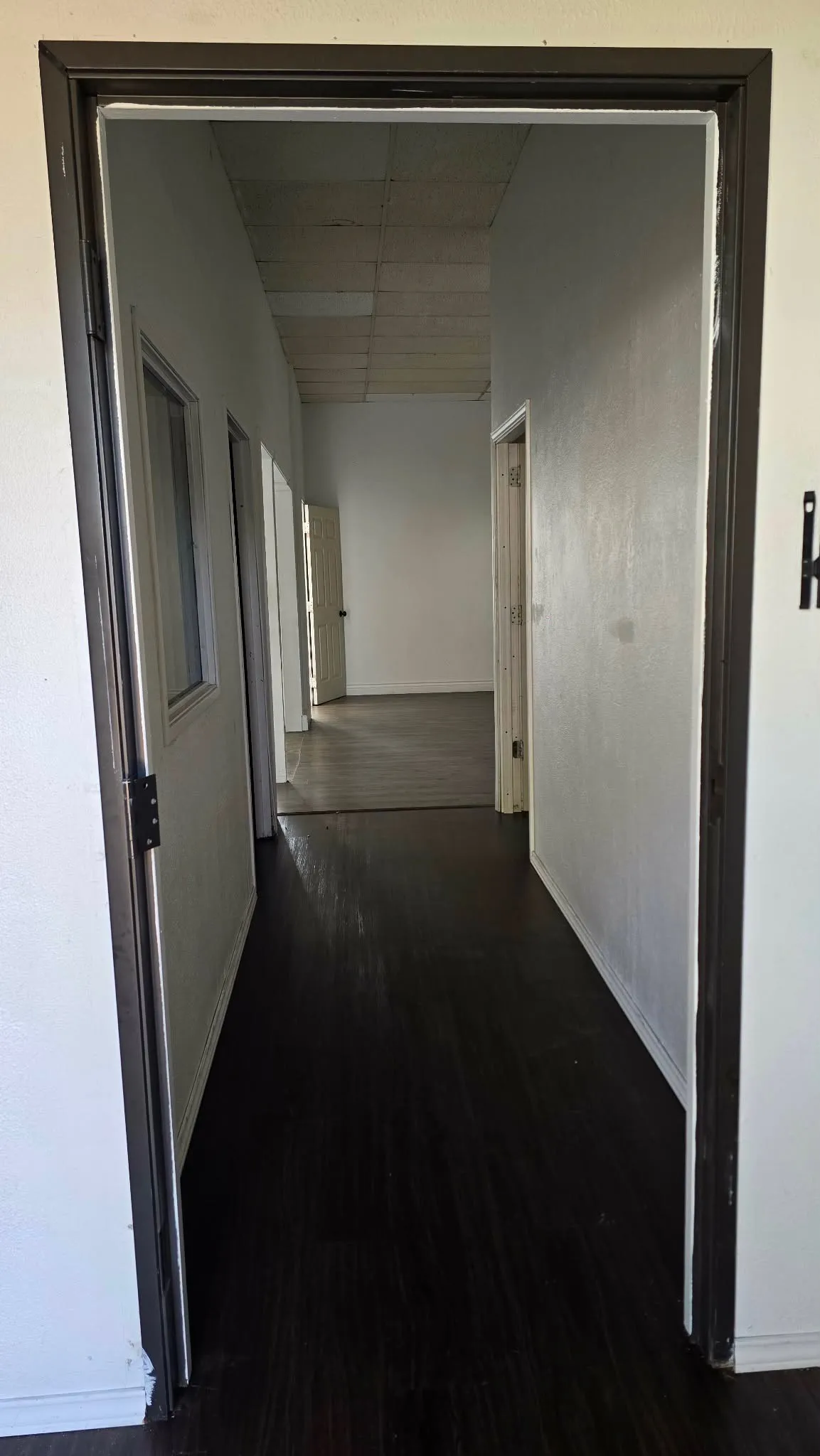 Hallway featuring dark wood-finish flooring, white walls, and dark door frames