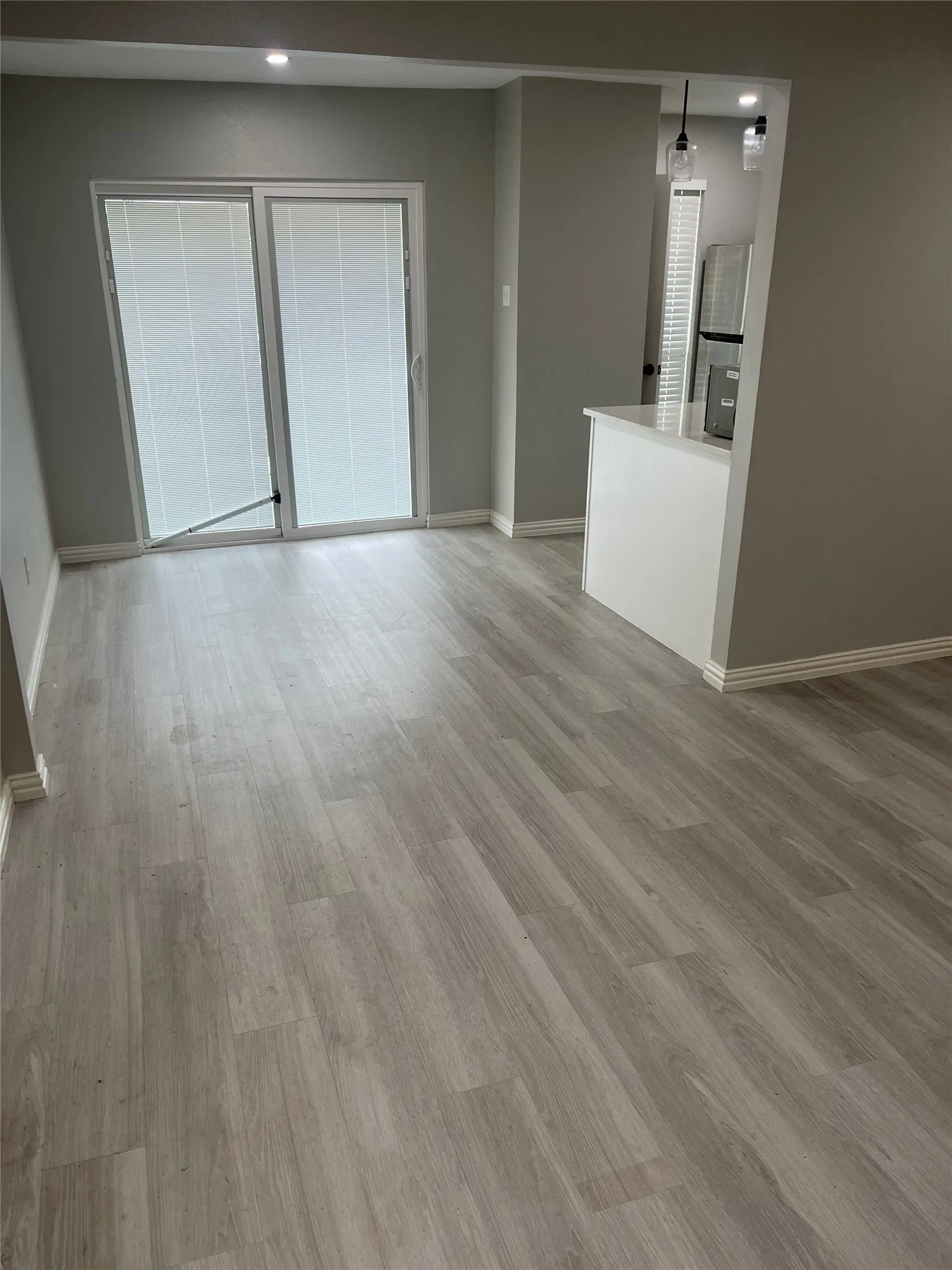 Spacious room with wood-finish flooring, light grey walls, and white baseboards
