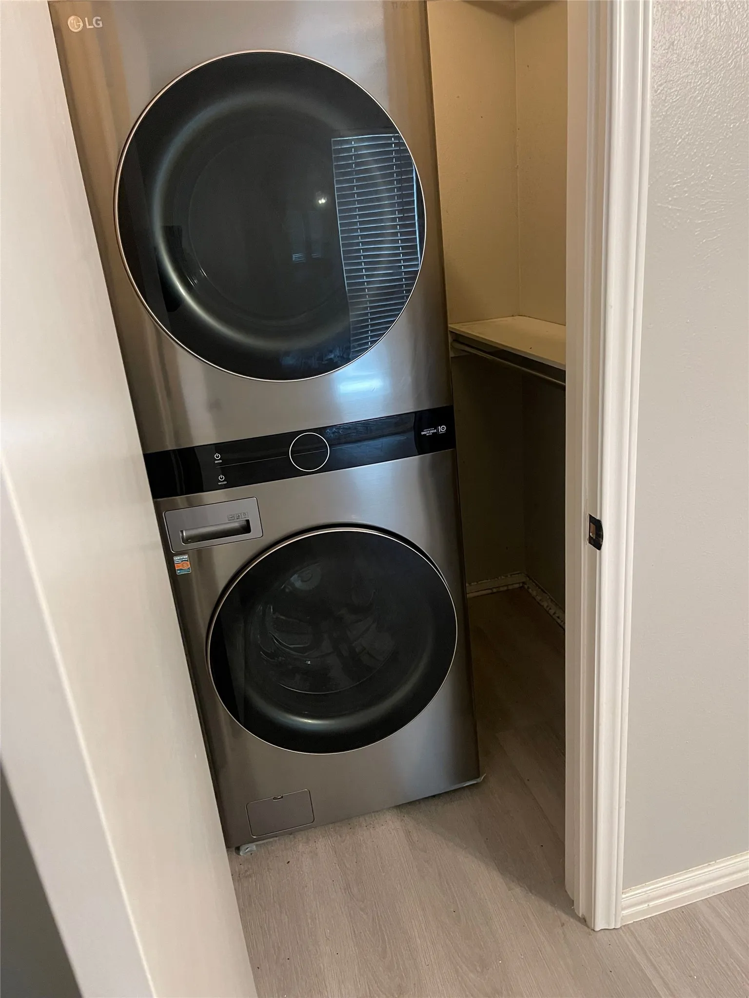 Stackable front-loading washer and dryer in a dedicated closet featuring a built-in shelf