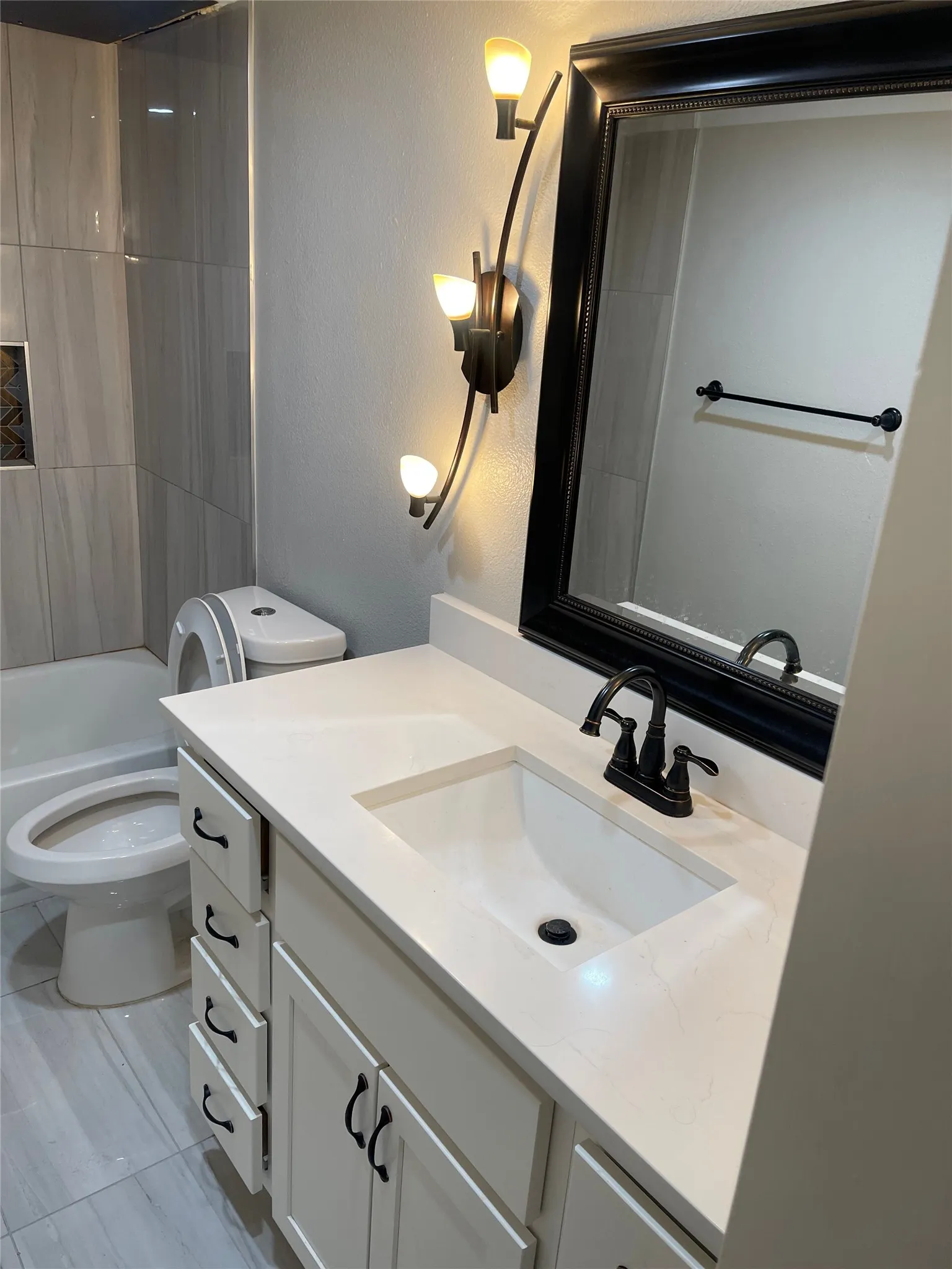 Bathroom featuring a white vanity with black hardware, a pristine countertop, and an integrated sink with a black faucet