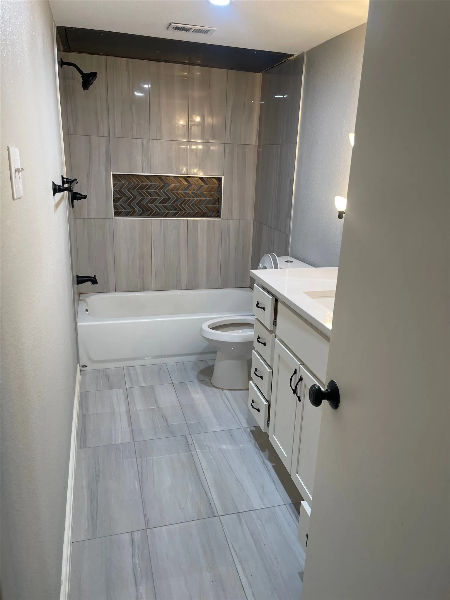 Bathroom featuring a white bathtub, gray large format tile flooring, and a vanity with a white countertop