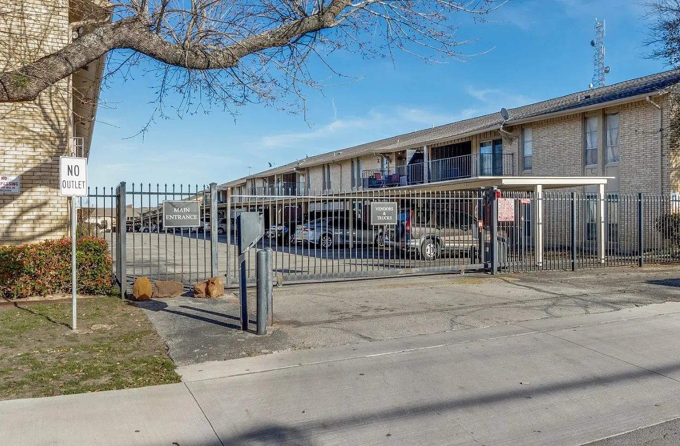 Gated entry to a multi-unit building featuring brick construction, covered parking, and private balconies