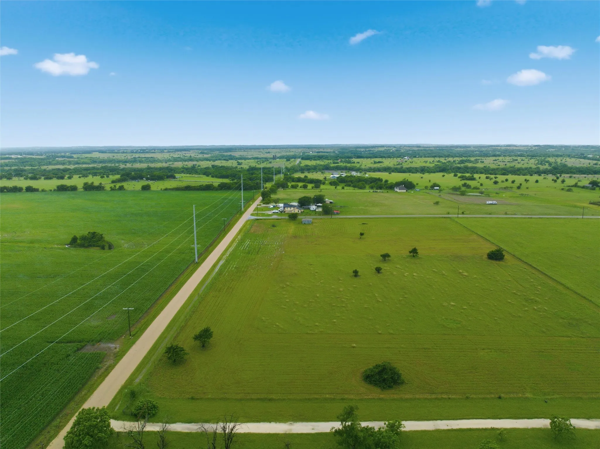 Expansive agricultural landscape featuring vast green fields and a clear blue sky