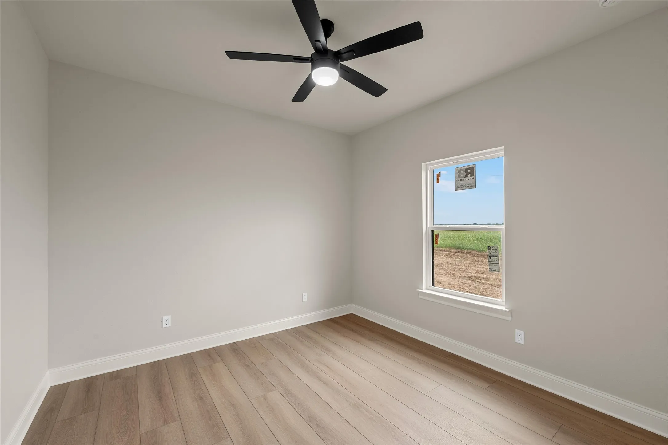 Room featuring wood-finish flooring, a ceiling fan with integrated lighting, a single window, white baseboards, and light-toned wall paint