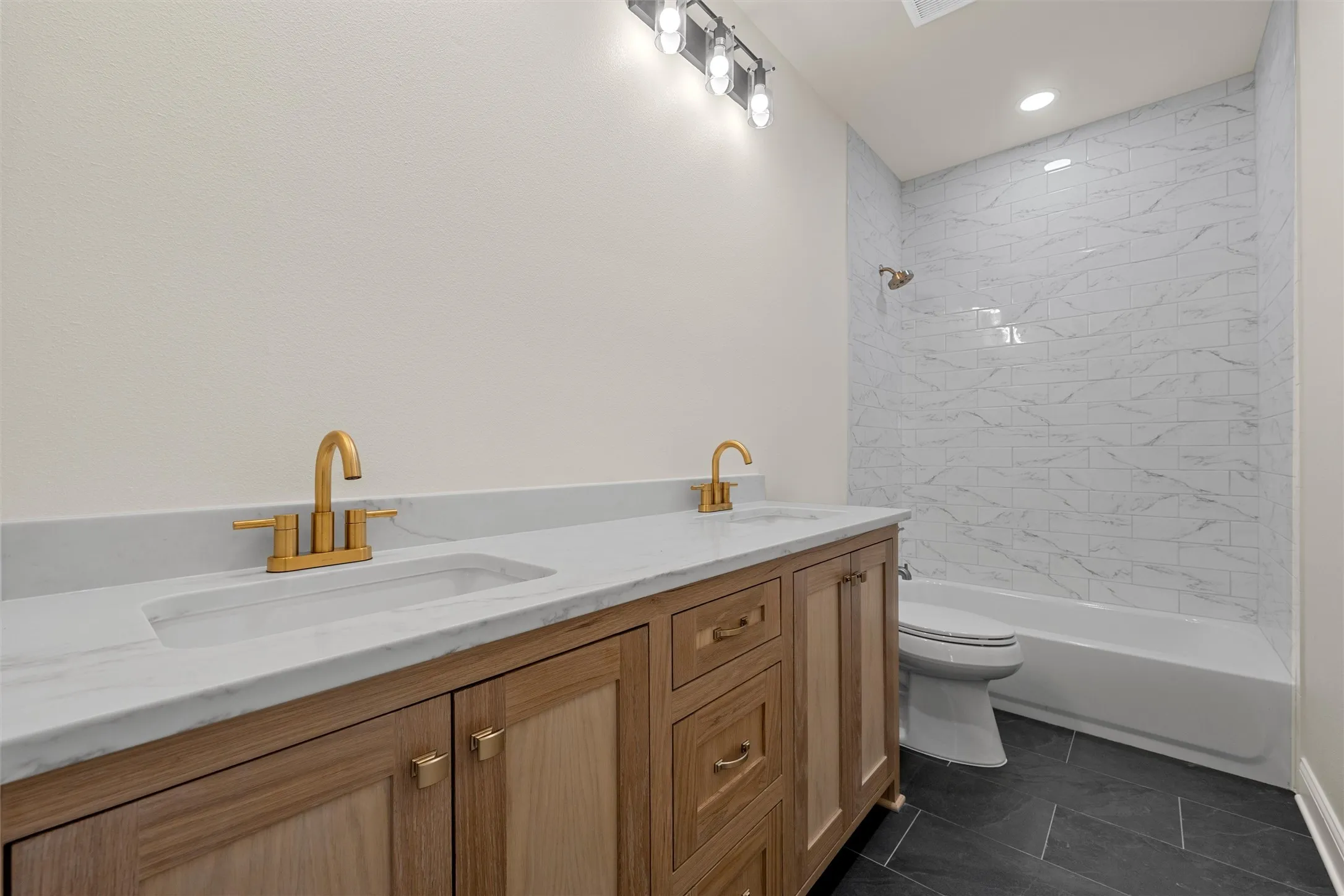 Bathroom featuring a dual vanity with a light wood-finish cabinet and white countertop