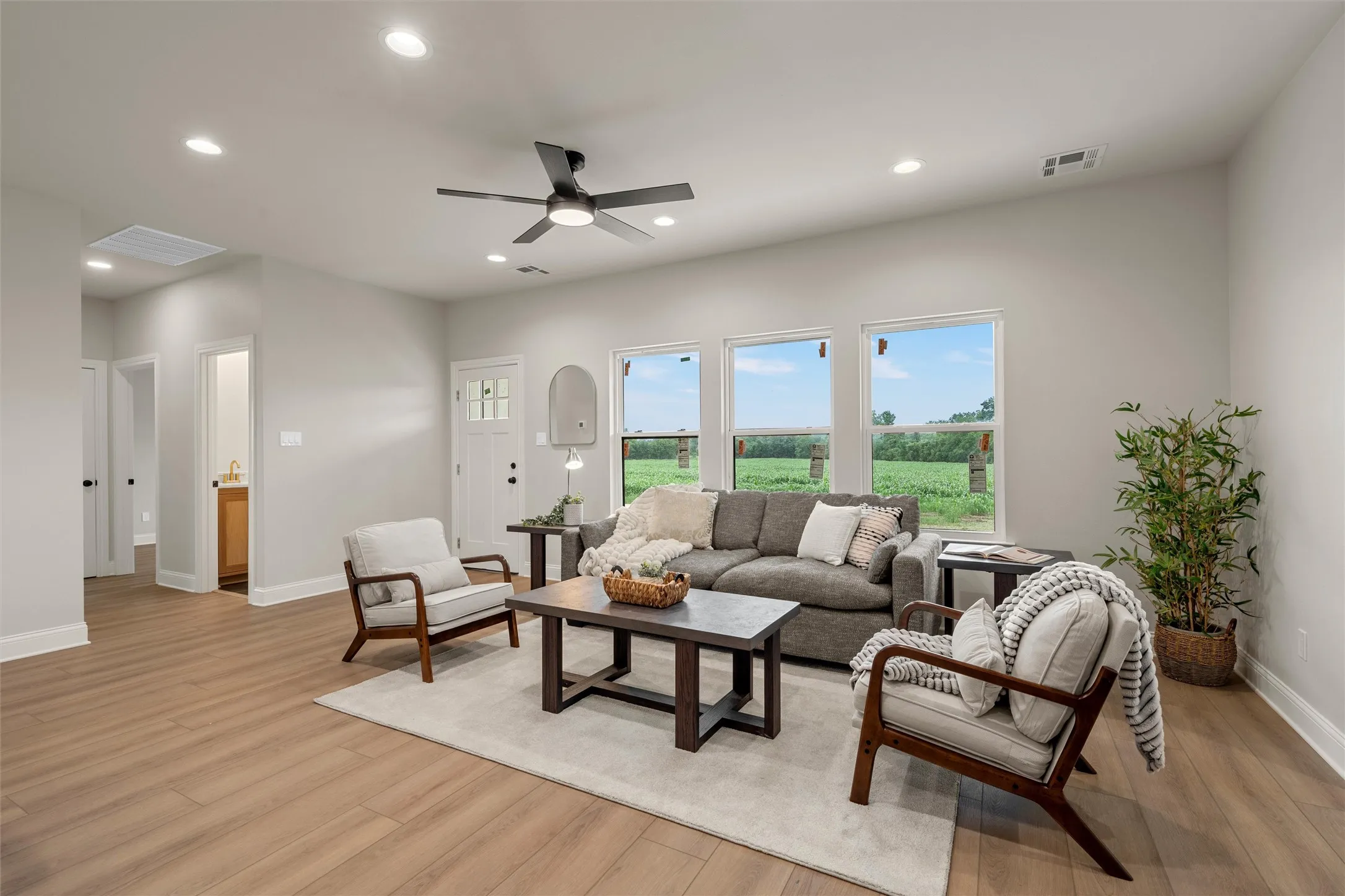 Living area featuring wood-finish flooring, recessed lighting, a ceiling fan, and multiple windows offering expansive exterior views