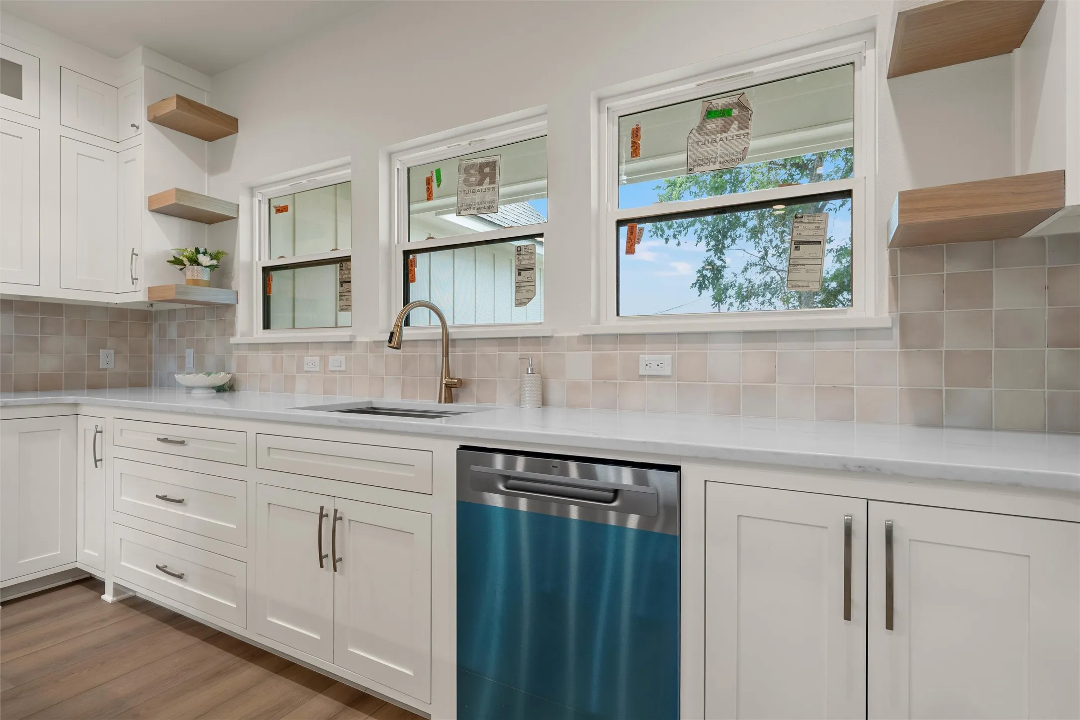 Kitchen featuring white cabinetry, light countertops, square tile backsplash, and a contemporary faucet