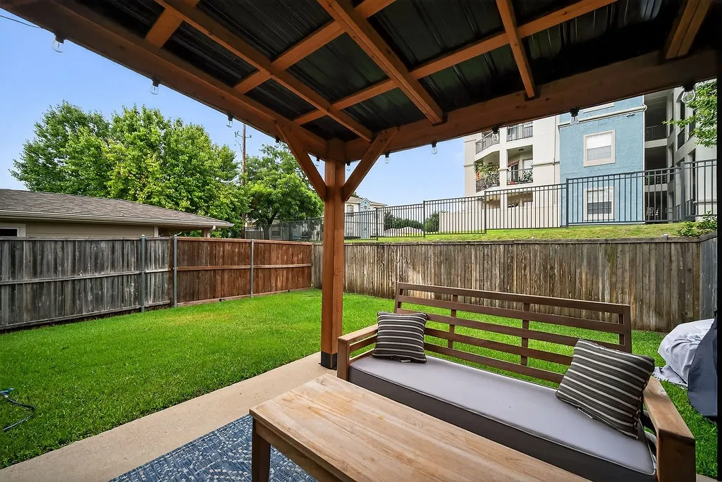 Covered patio featuring a wood-beam structure and corrugated metal roof