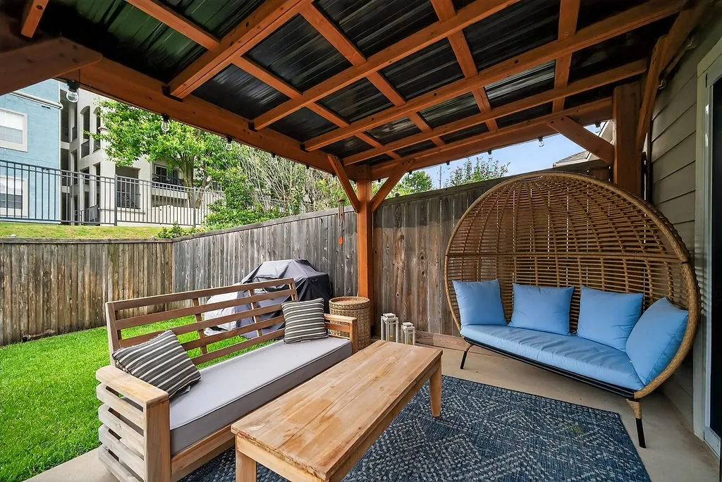 Covered patio featuring a wood beam and metal roof structure, concrete flooring, and a wood fence enclosure