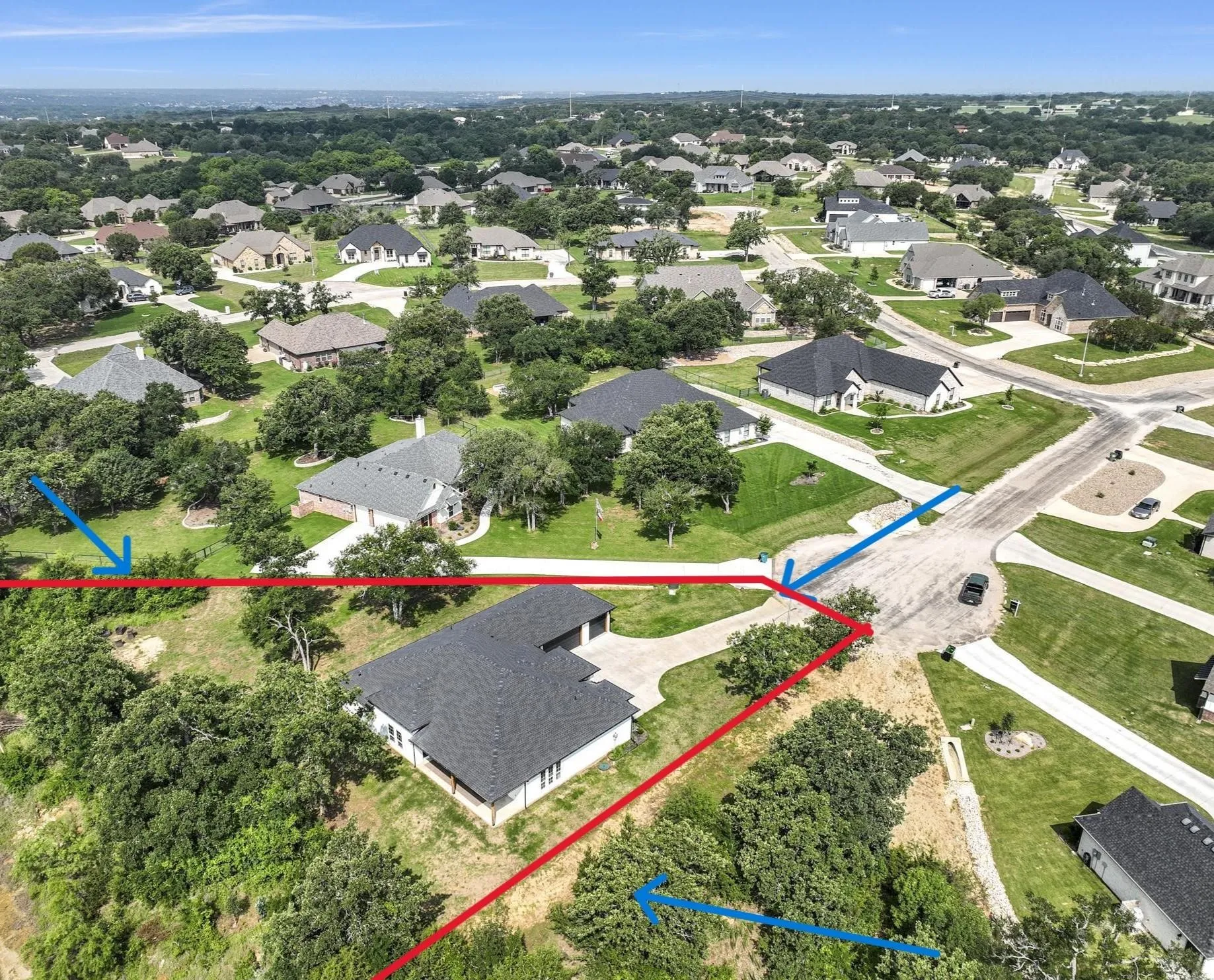 Aerial perspective showcasing a residential property with a dark shingle roof and a light-colored exterior