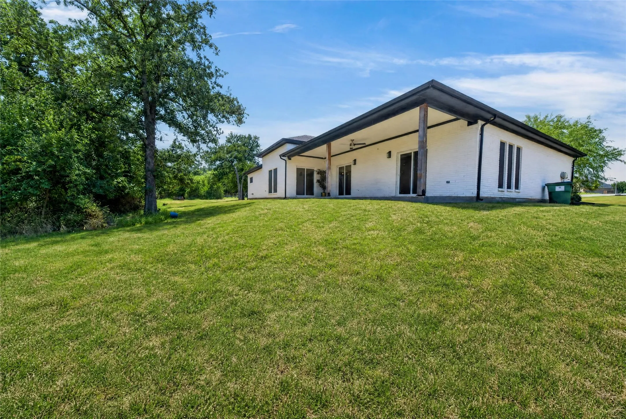 Expansive green lawn with mature trees and a contemporary white brick exterior