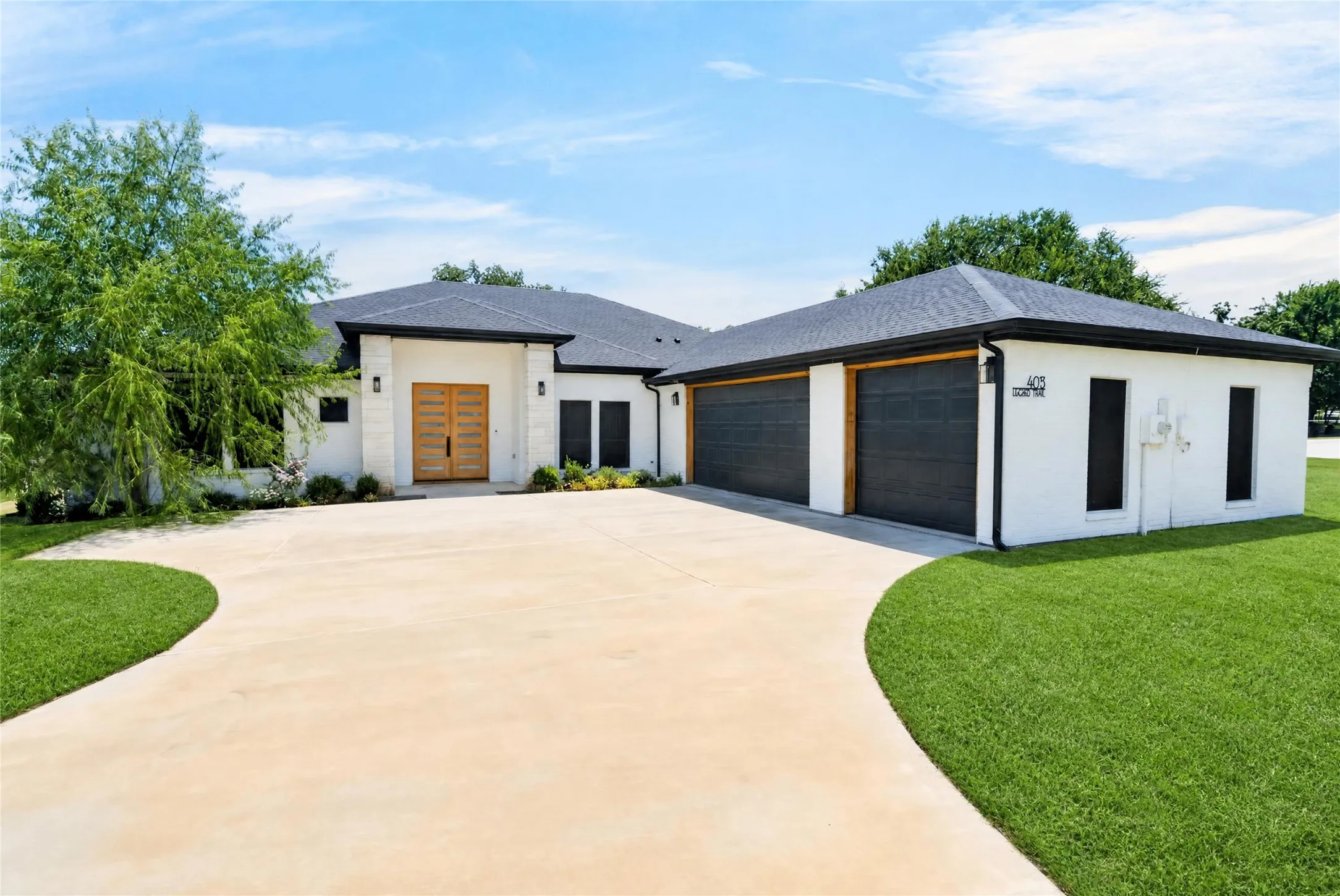 Contemporary white brick exterior with a dark shingle roof, featuring a light wood double entry door