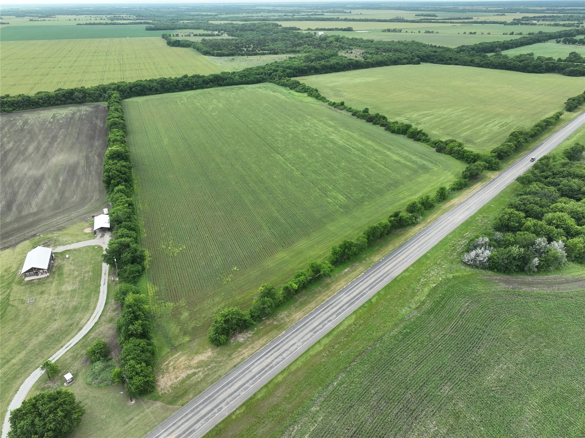 Expansive agricultural land featuring a paved road frontage and multiple cultivated fields