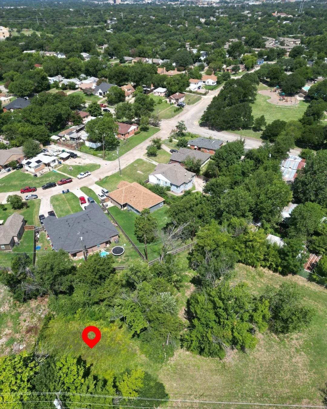 Expansive vacant lot featuring varied terrain and mature trees