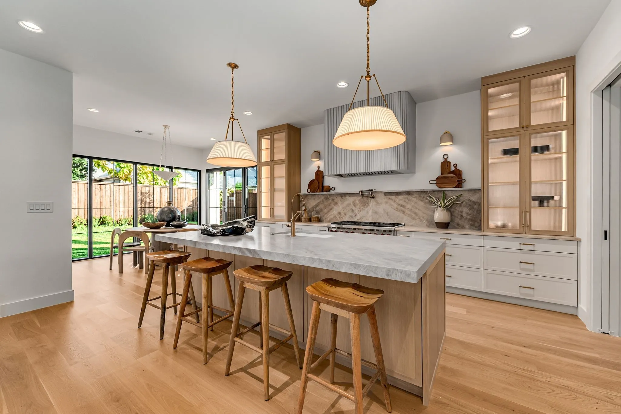 Kitchen with glass insert cabinets, a breakfast bar area, decorative backsplash, a large island, and decorative light fixtures