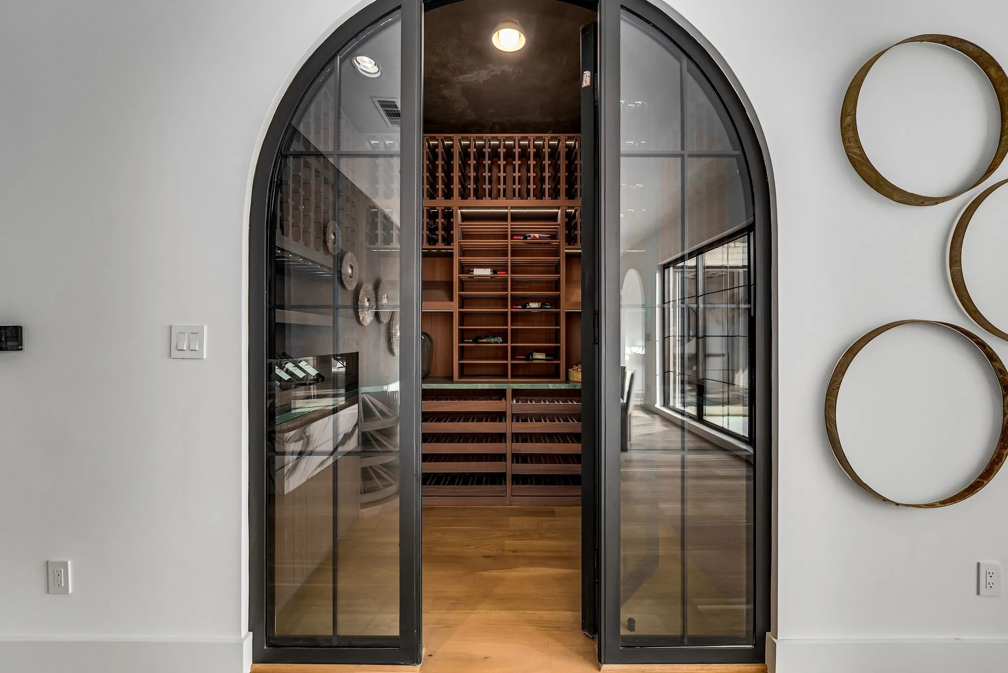 Wine room featuring a sauna / steam room, arched walkways, and light wood-style flooring