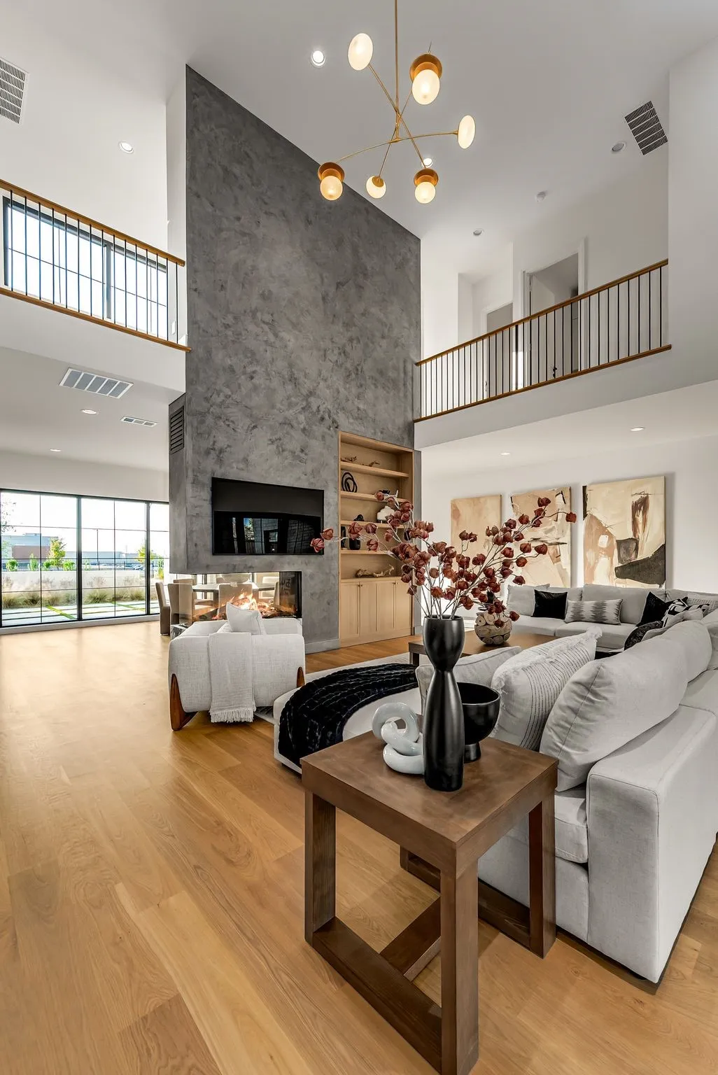 Living area with a high ceiling, light wood finished floors, recessed lighting, a chandelier, and a multi sided fireplace
