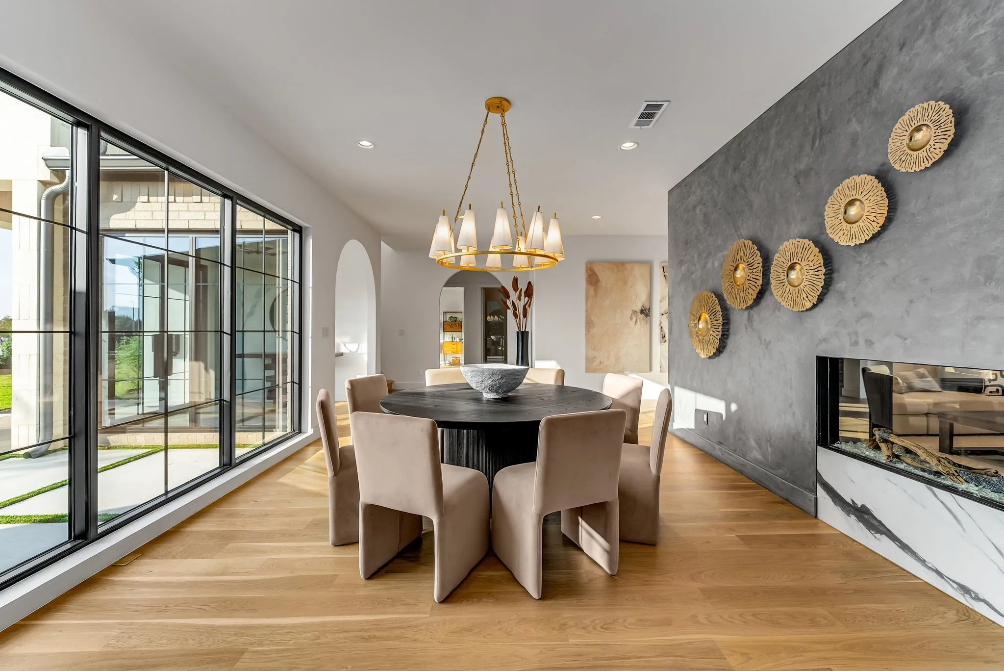 Dining area featuring light wood-style floors, arched walkways, recessed lighting, a premium fireplace, and an accent wall