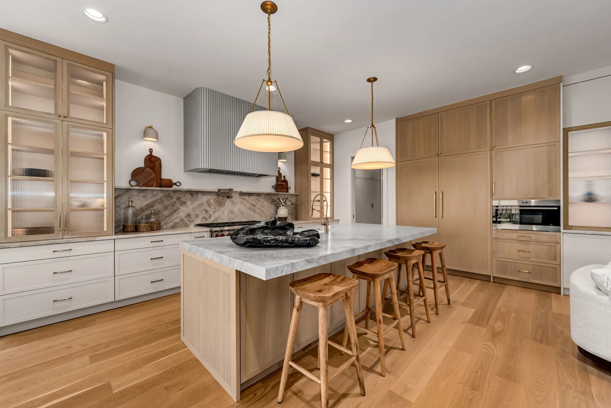 Kitchen with light brown cabinets, exhaust hood, a breakfast bar area, light wood-type flooring, and recessed lighting