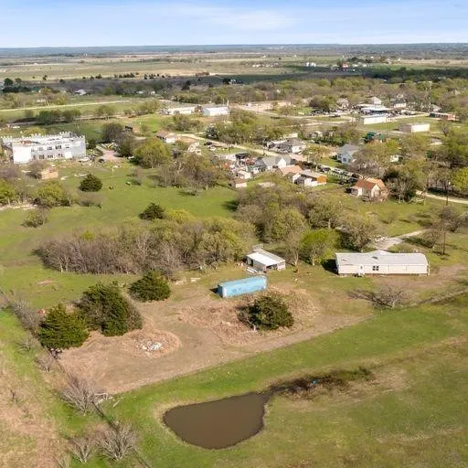 Expansive land parcel featuring a natural pond, scattered trees, and clear blue skies