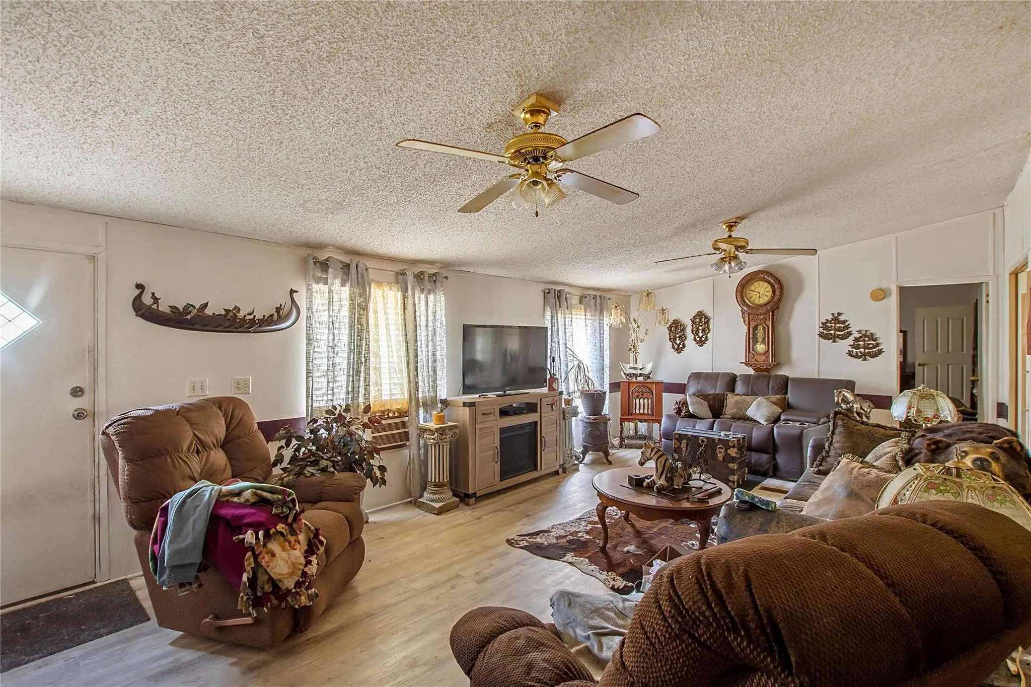 Spacious living area featuring wood-finish flooring and multiple ceiling fans
