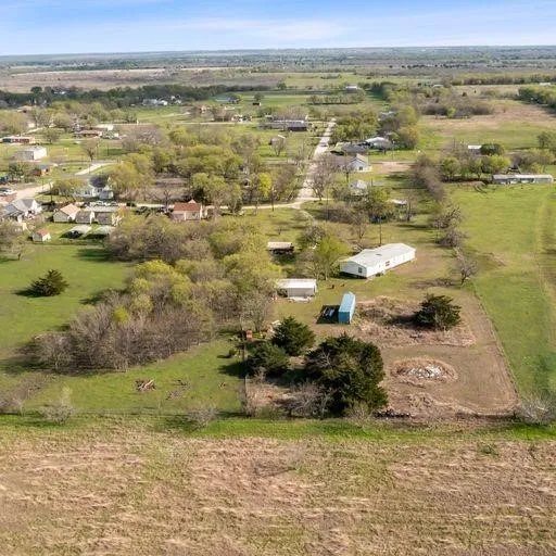 Expansive lot featuring a single-story residence, multiple outbuildings, mature trees, and open land areas