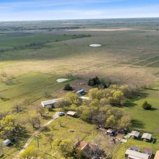 Expansive rural property featuring multiple structures, open fields, and two visible ponds