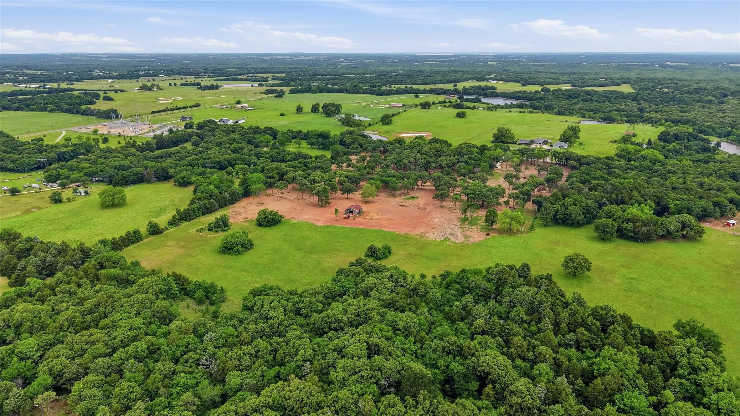 Expansive property featuring a central clearing, surrounded by dense mature trees and open green spaces