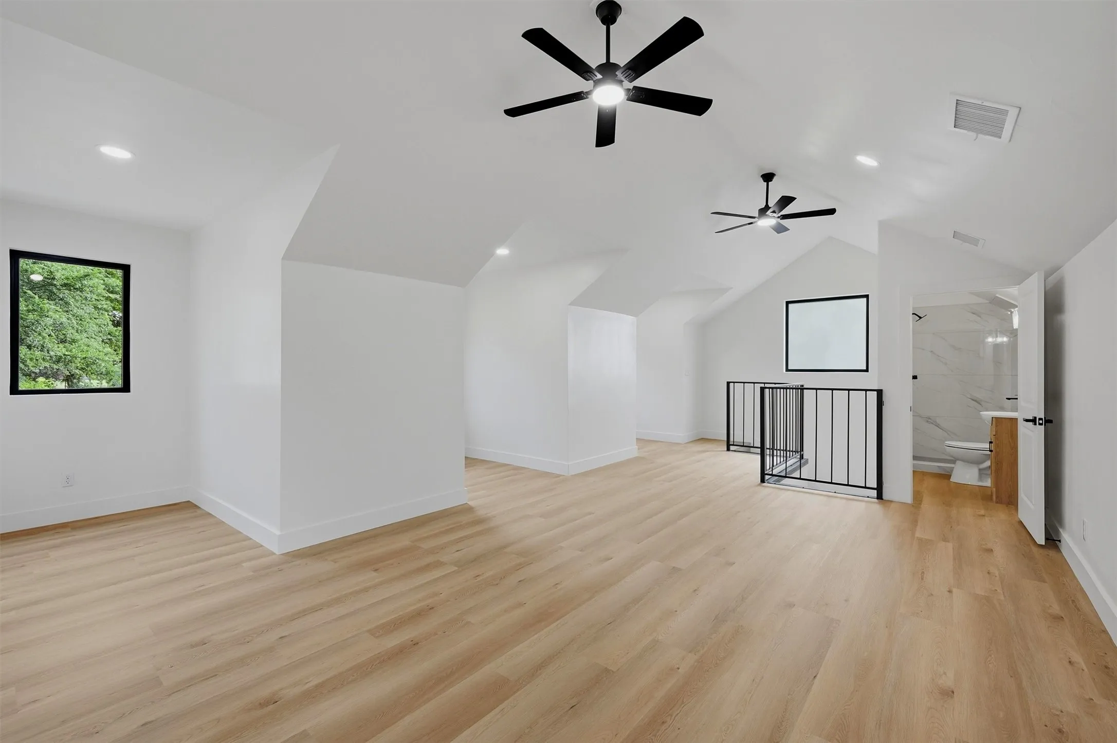 Spacious loft area featuring light wood-finish flooring, vaulted ceilings, and recessed lighting