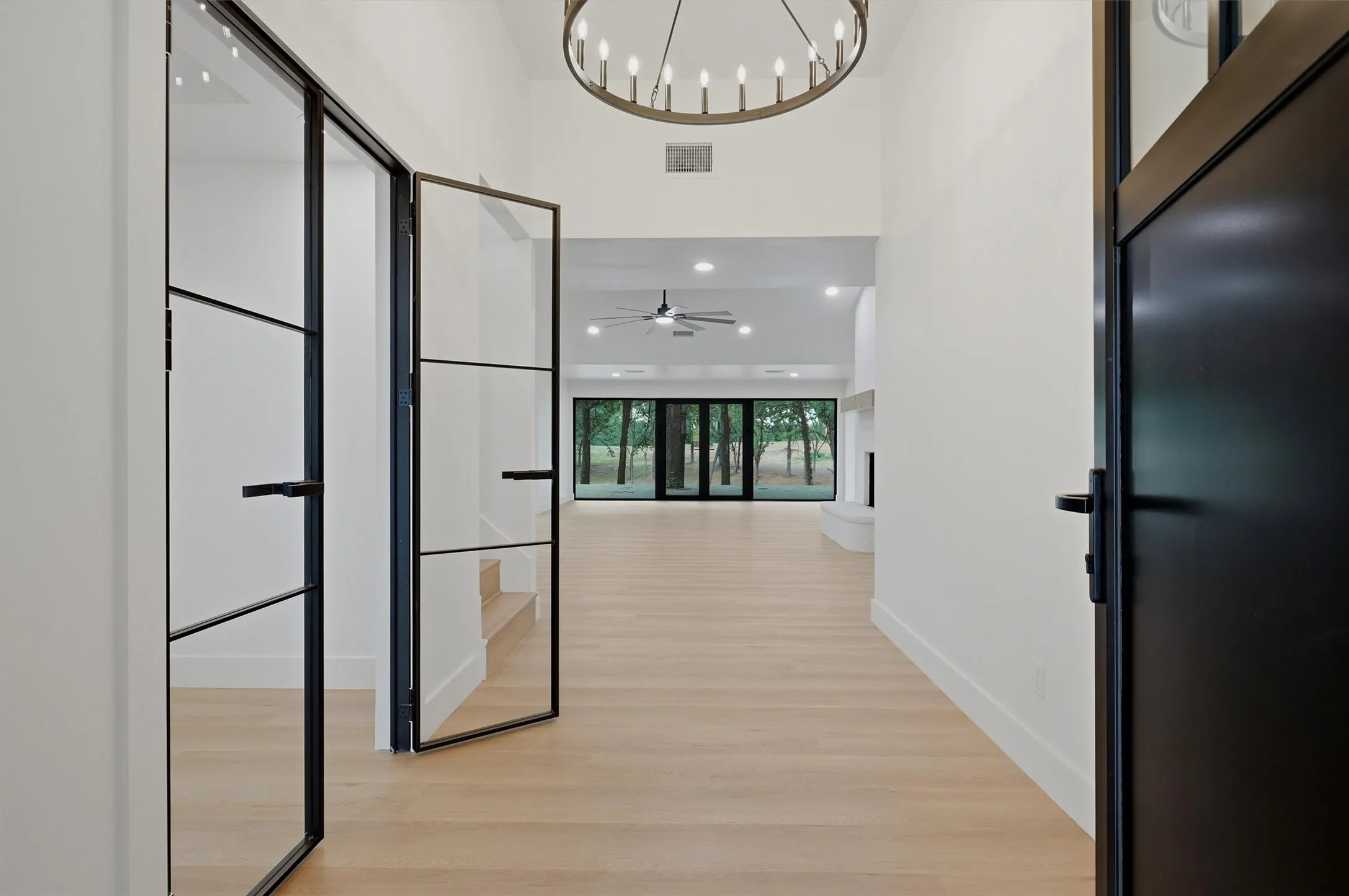 Double-height entry foyer featuring a large chandelier and light wood-finish flooring