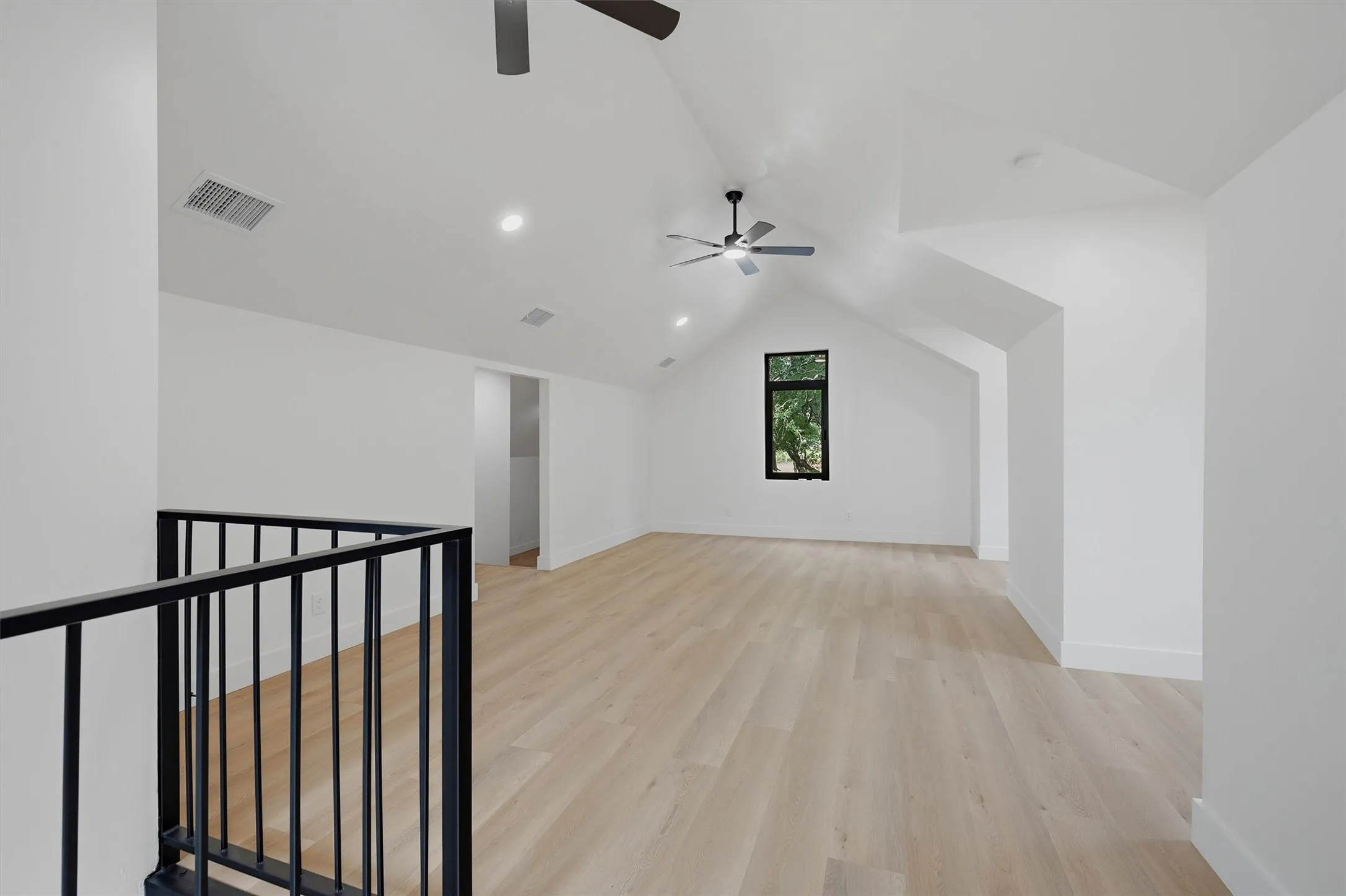 Expansive loft space featuring vaulted ceilings, recessed lighting, and wood-finish flooring