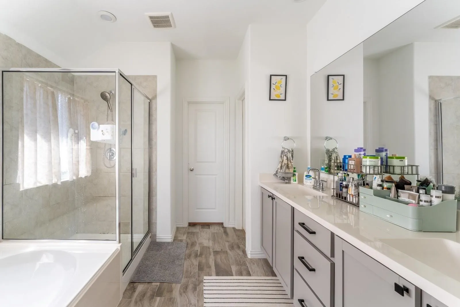 Bathroom featuring wood-type flooring, double sink vanity, and plus walk in shower