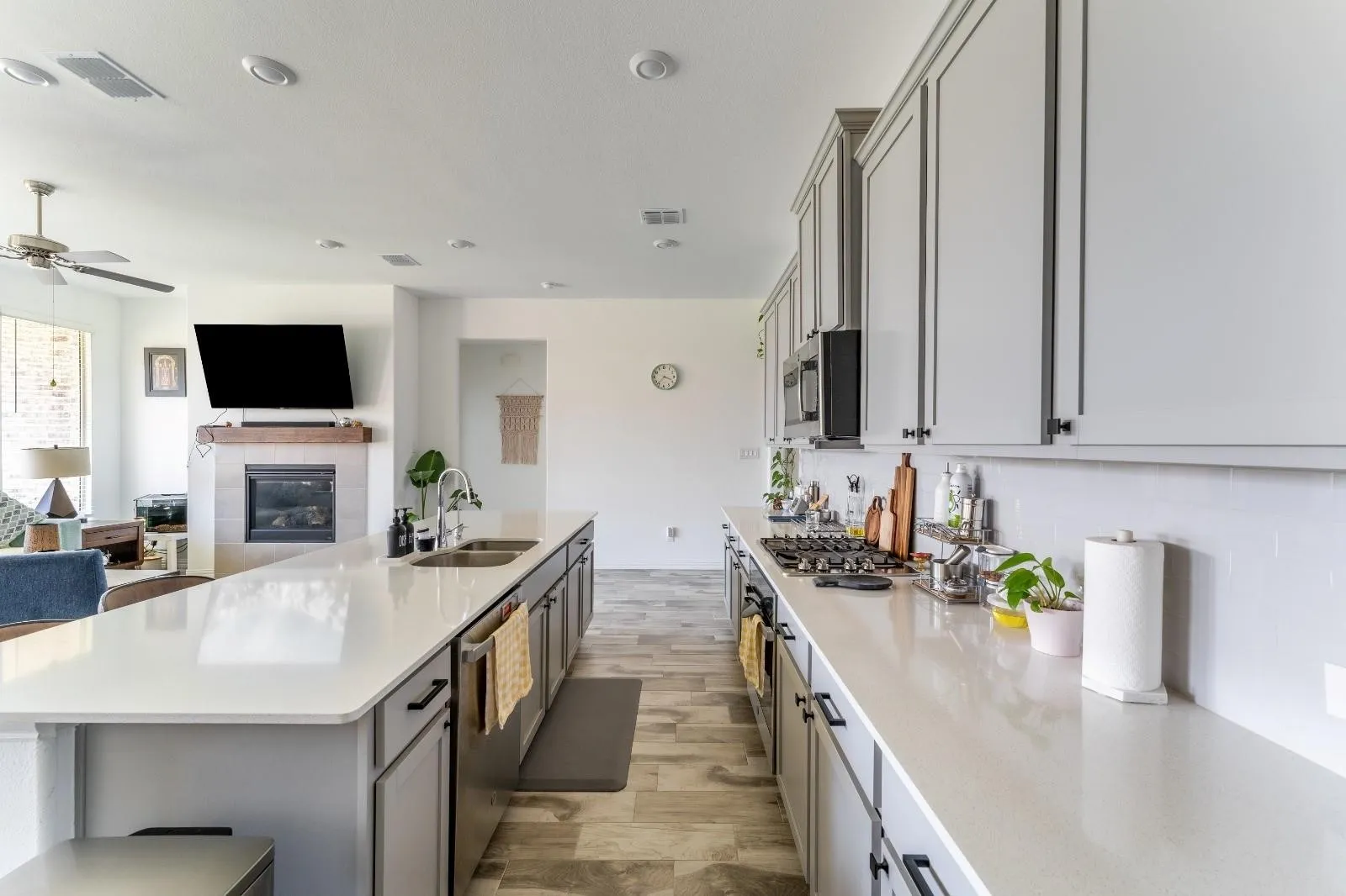 Kitchen featuring appliances with stainless steel finishes, sink, gray cabinetry, a tiled fireplace, and light hardwood / wood-style flooring