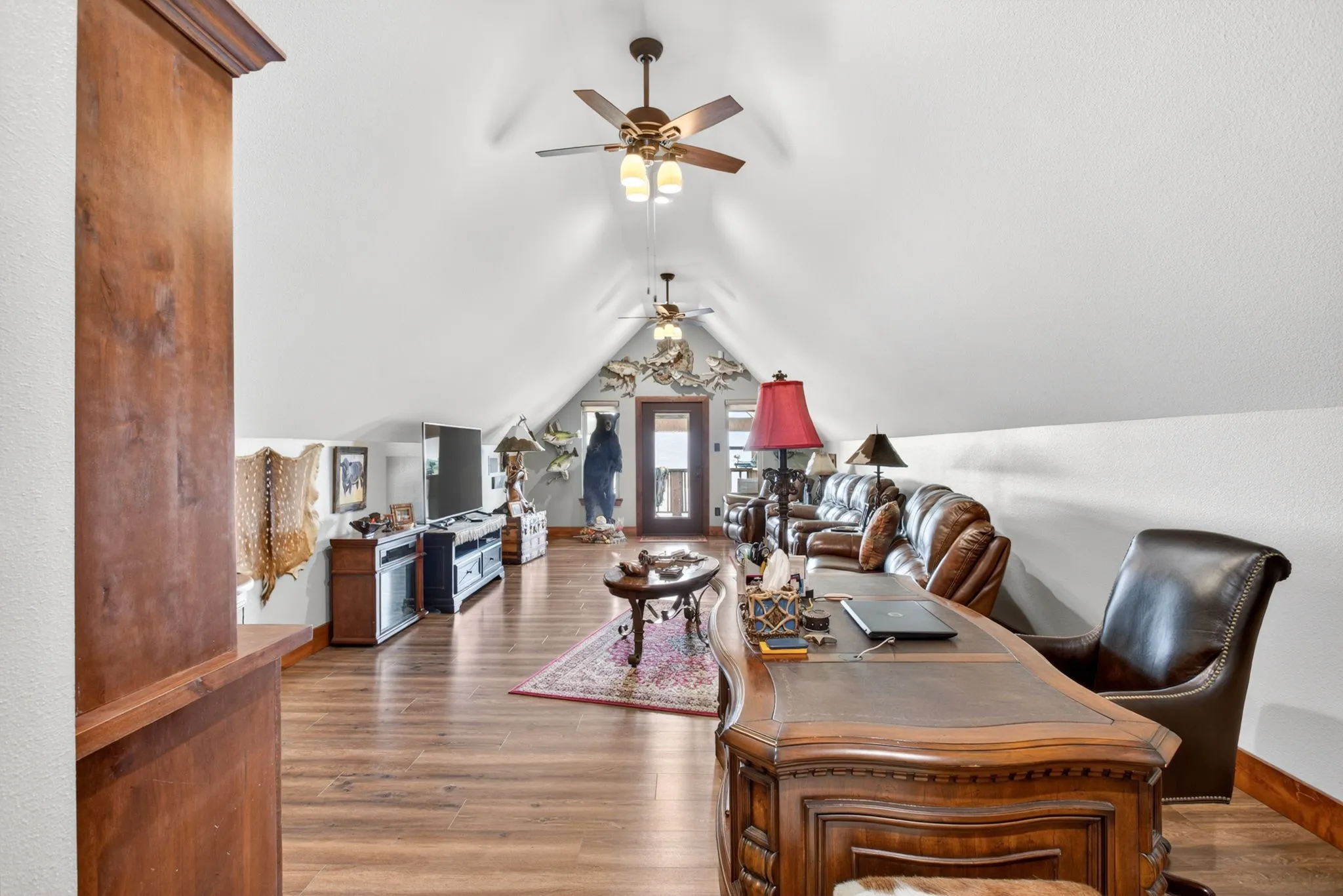 Spacious bonus room featuring a vaulted ceiling, wood-finish flooring, and multiple ceiling fans