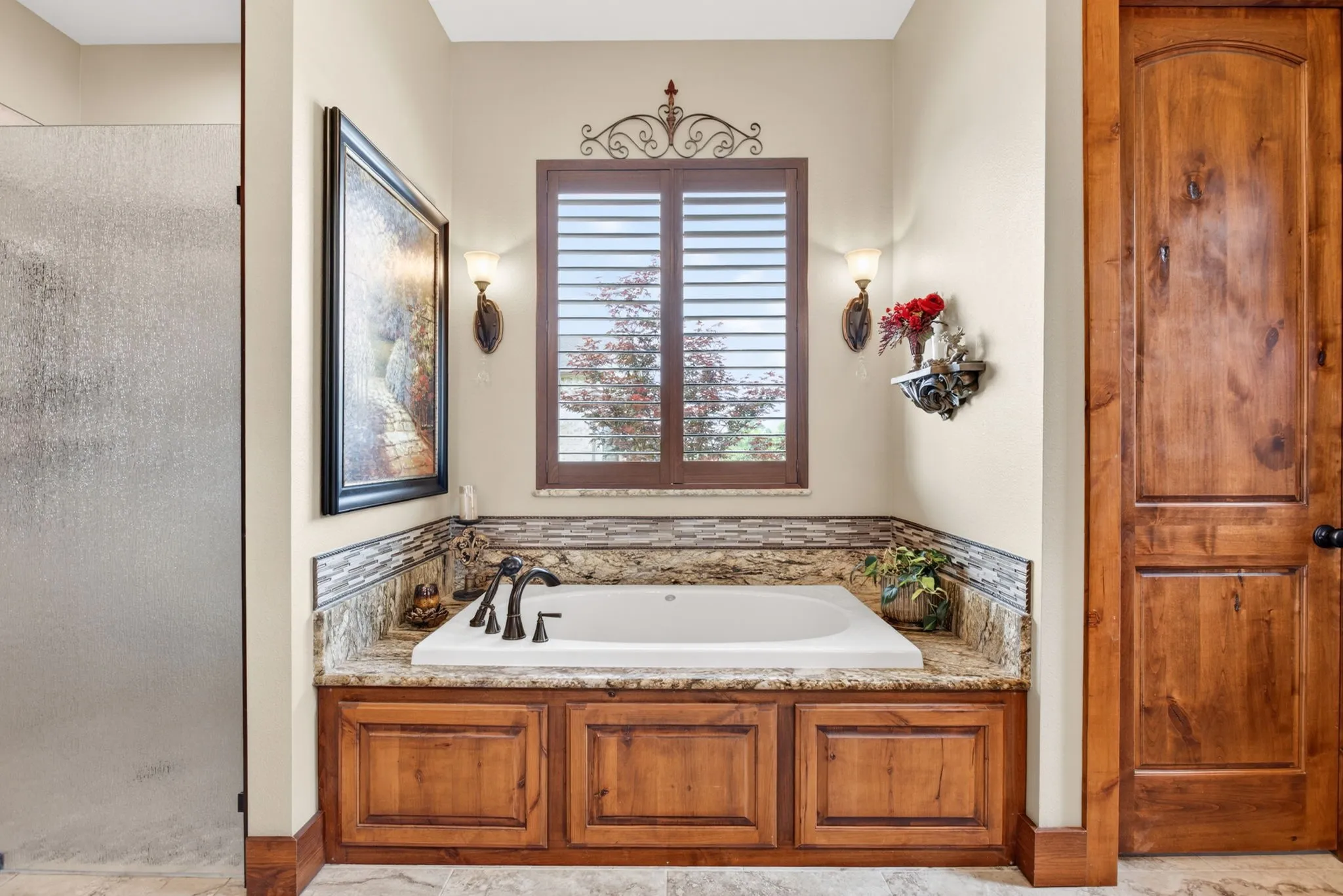 Built-in soaking tub with a stone surround and mosaic tile backsplash
