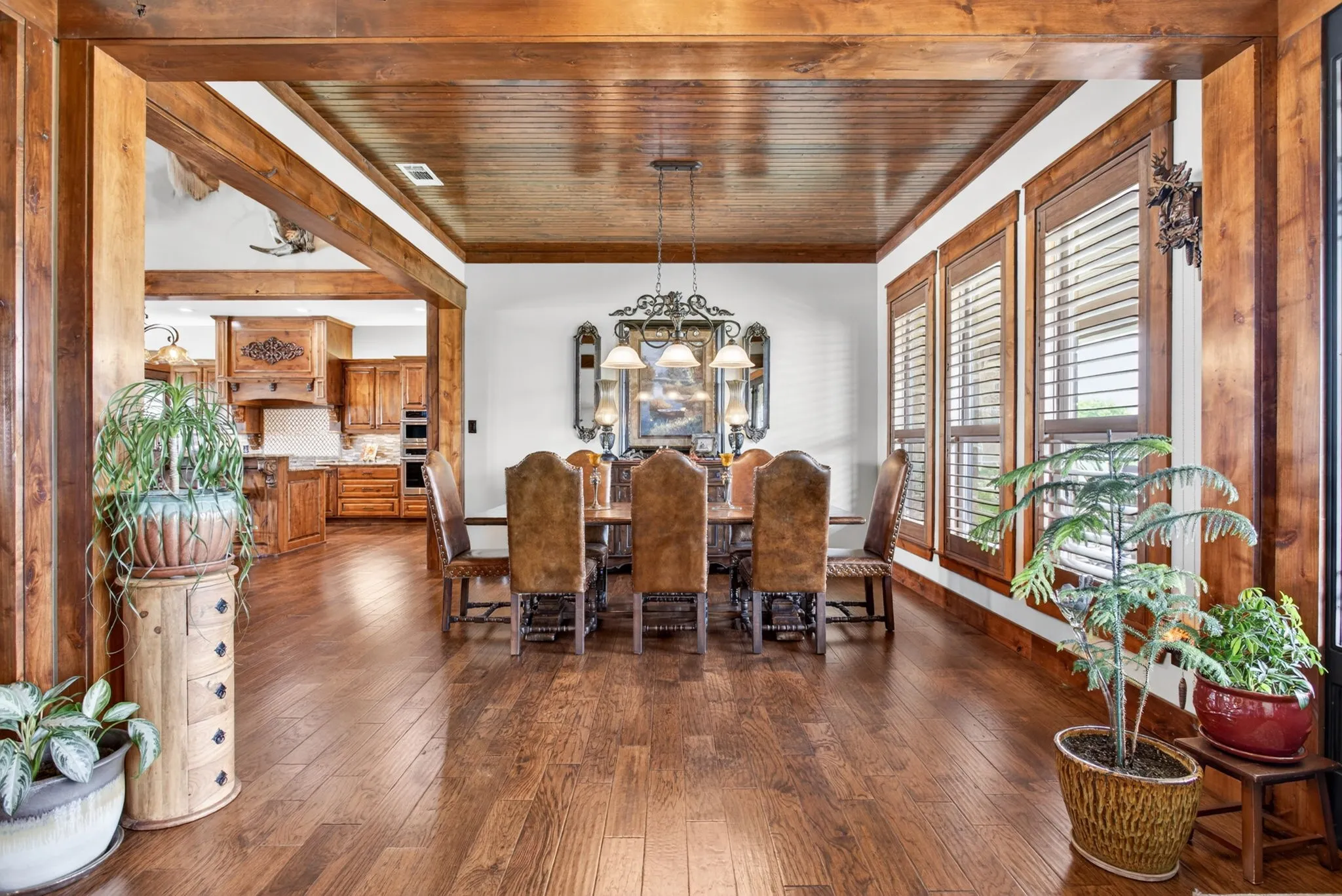 Formal dining area featuring rich wood-finish flooring, a coordinating wood-paneled ceiling, and robust wood trim