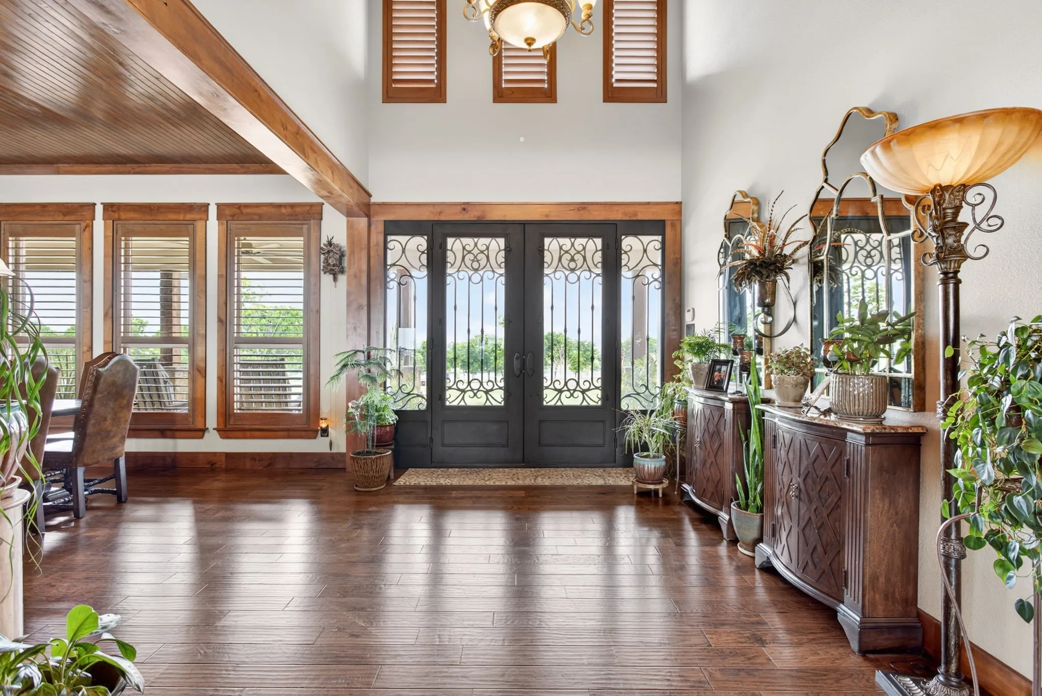 Grand foyer featuring dark wood-finish flooring, a double entry door with decorative ironwork, and a vaulted ceiling